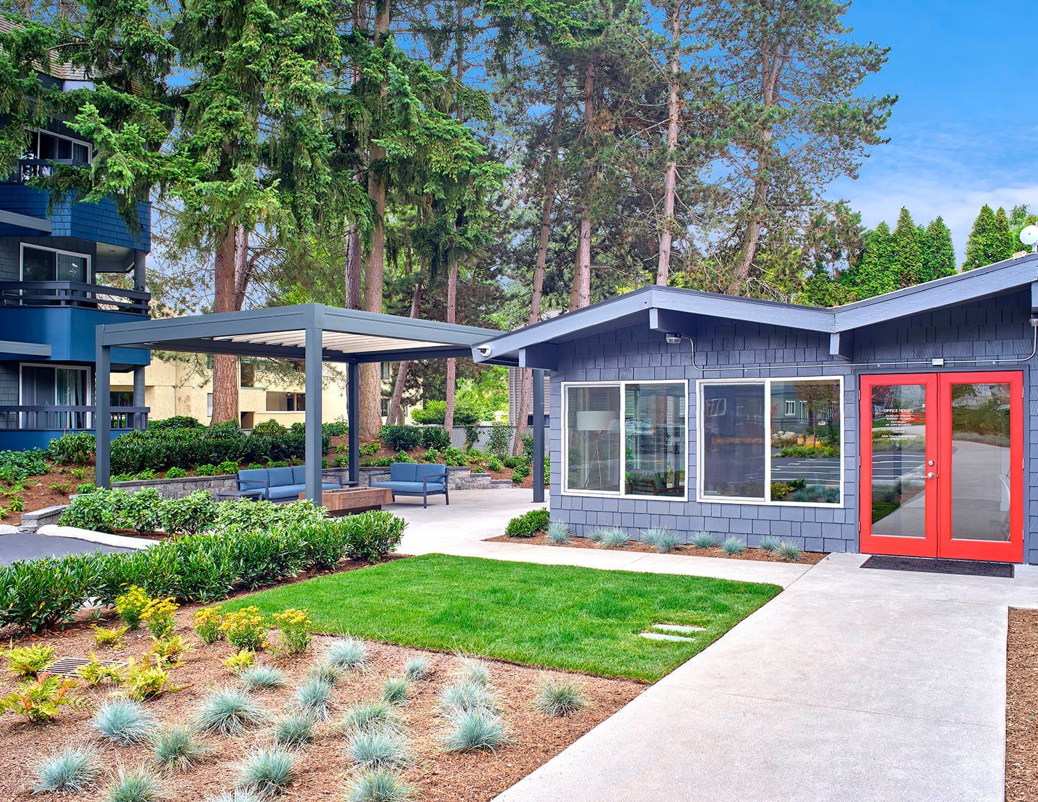 Outdoor patio area with a blue trellis, patio furniture, and a blue building with bright red double doors.