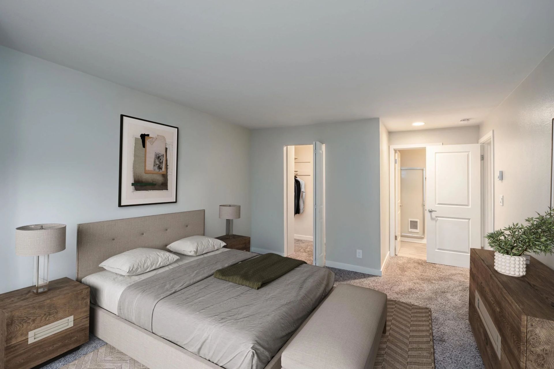 A bedroom with a grey upholstered bed, two wooden nightstands, a piece of wall art, and an open doorway to a walk-in closet.