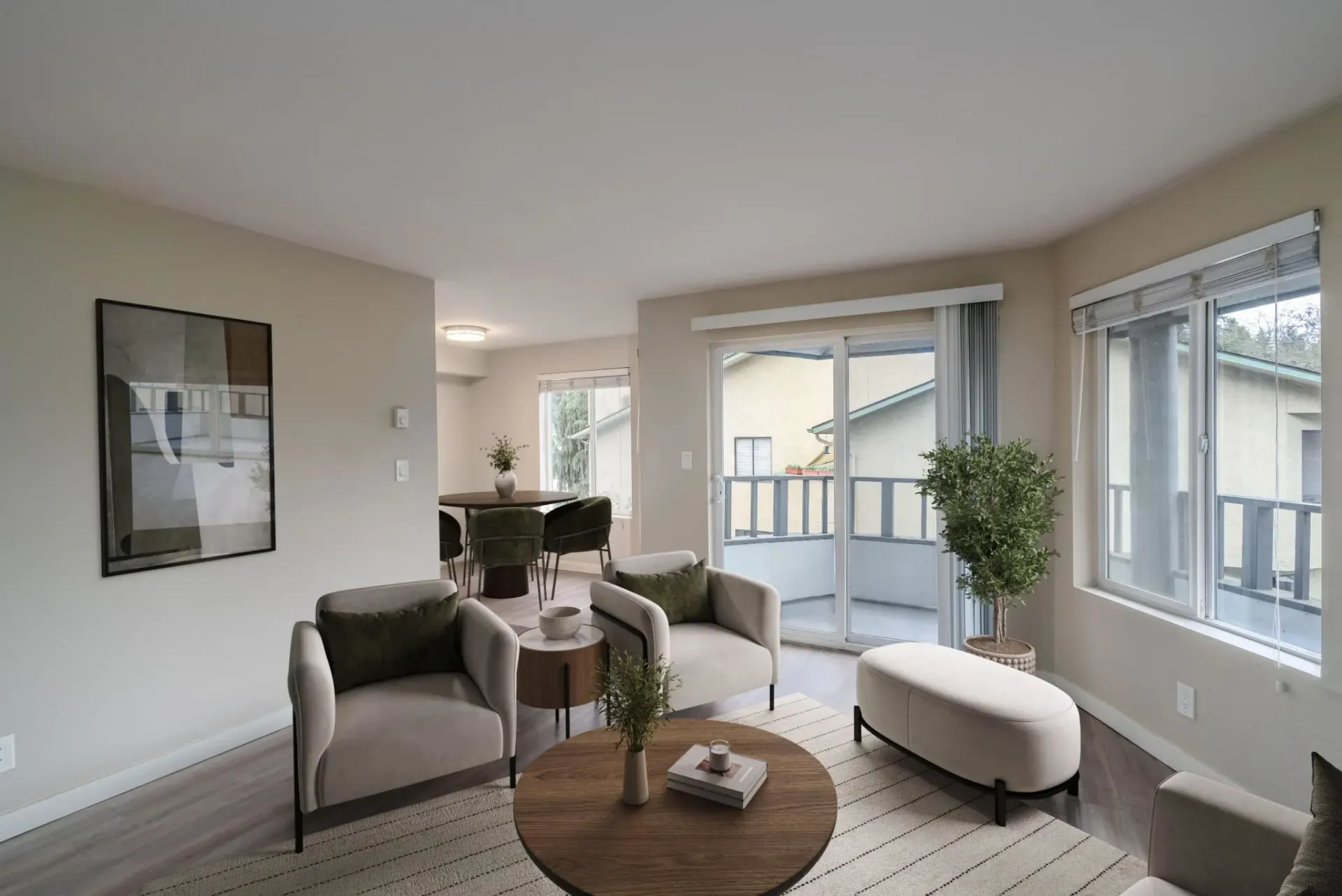 A bright living room features neutral armchairs, a wooden coffee table, a small ottoman, and a dining area in the back.