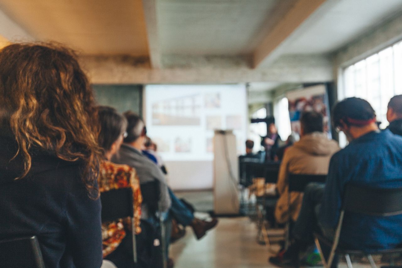 A group of people are sitting in chairs in front of a projector screen.