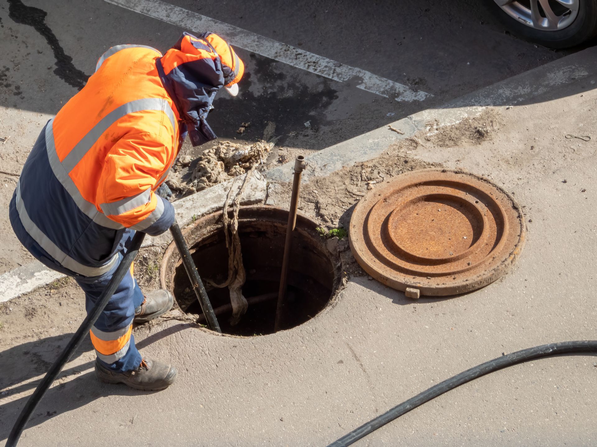 Worker over the open sewer hatch.