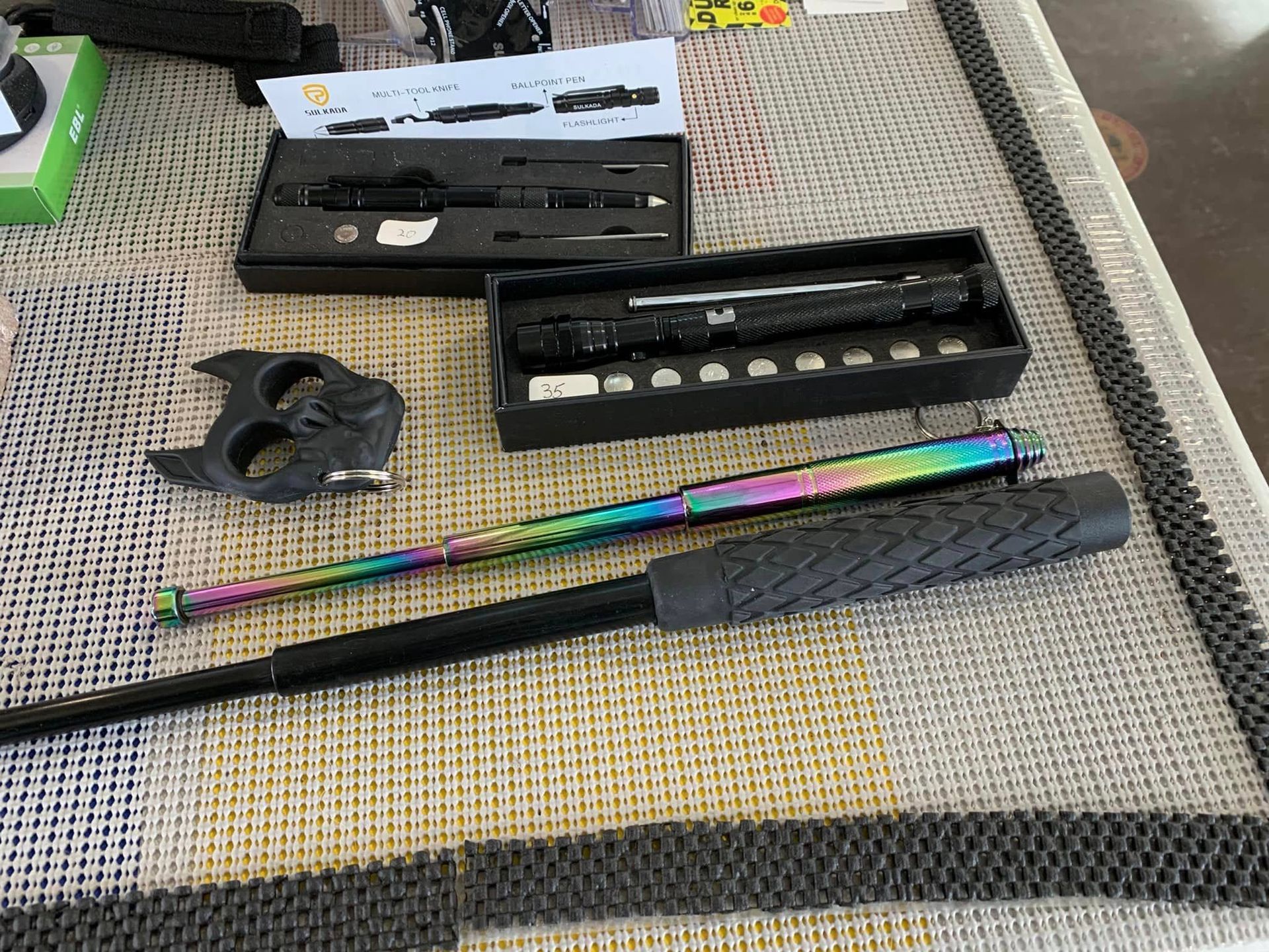 Items on a table: expandable batons, brass knuckles, and a box of tools.