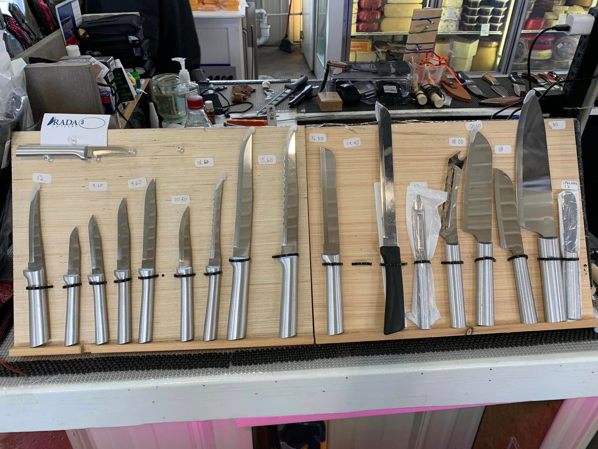 Knives displayed for sale on wooden boards. Various sizes and styles with silver handles.