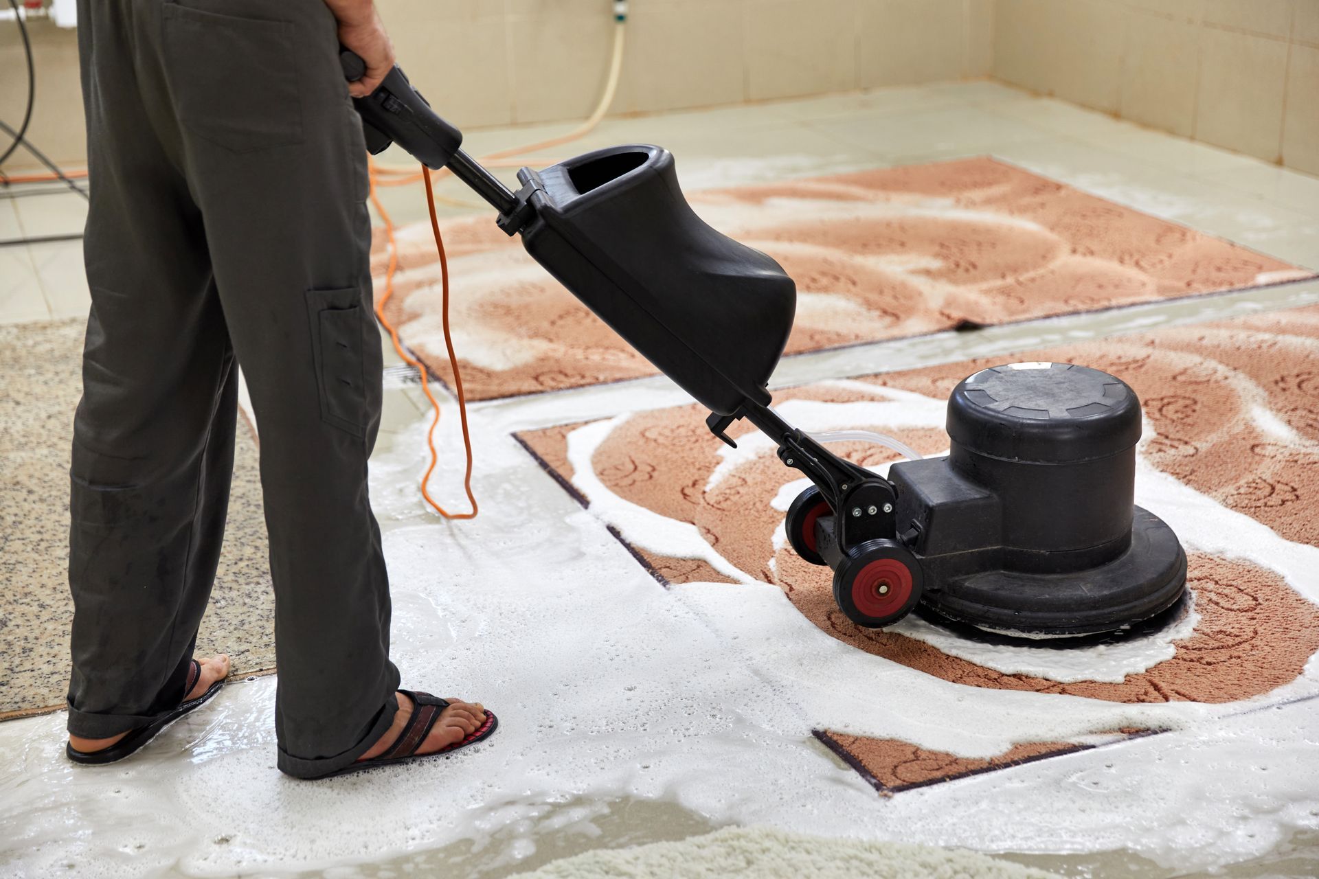a man is using a machine to clean a rug on the floor .
