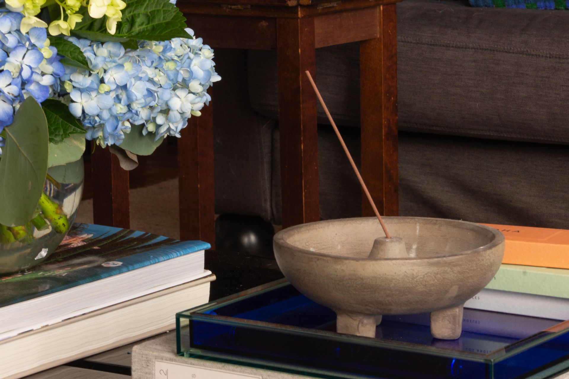 a moody living room vignette with an acrylic tray and concrete incense burner