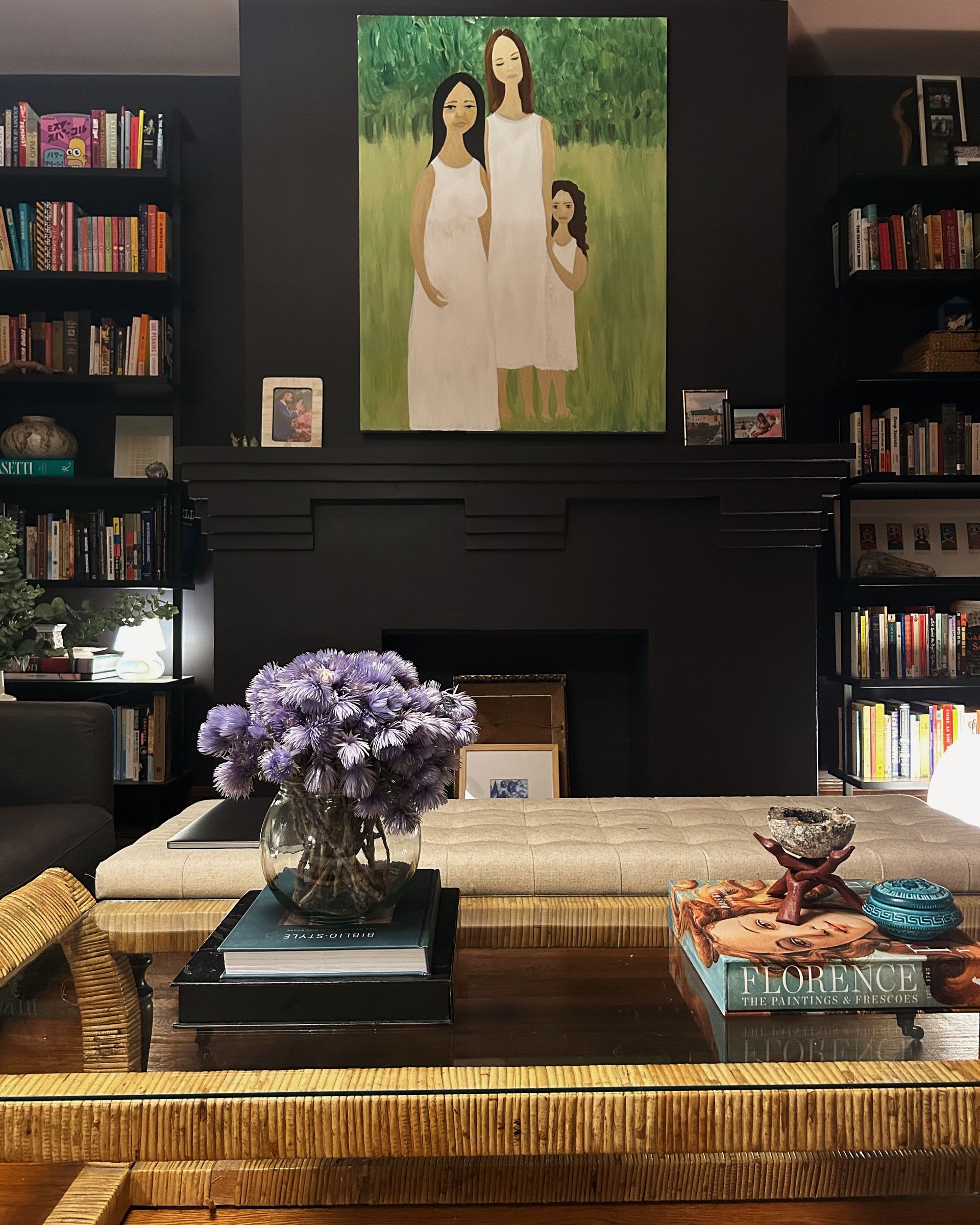 a dark and moody living room with a black wall and fireplace with bookshelves on either side