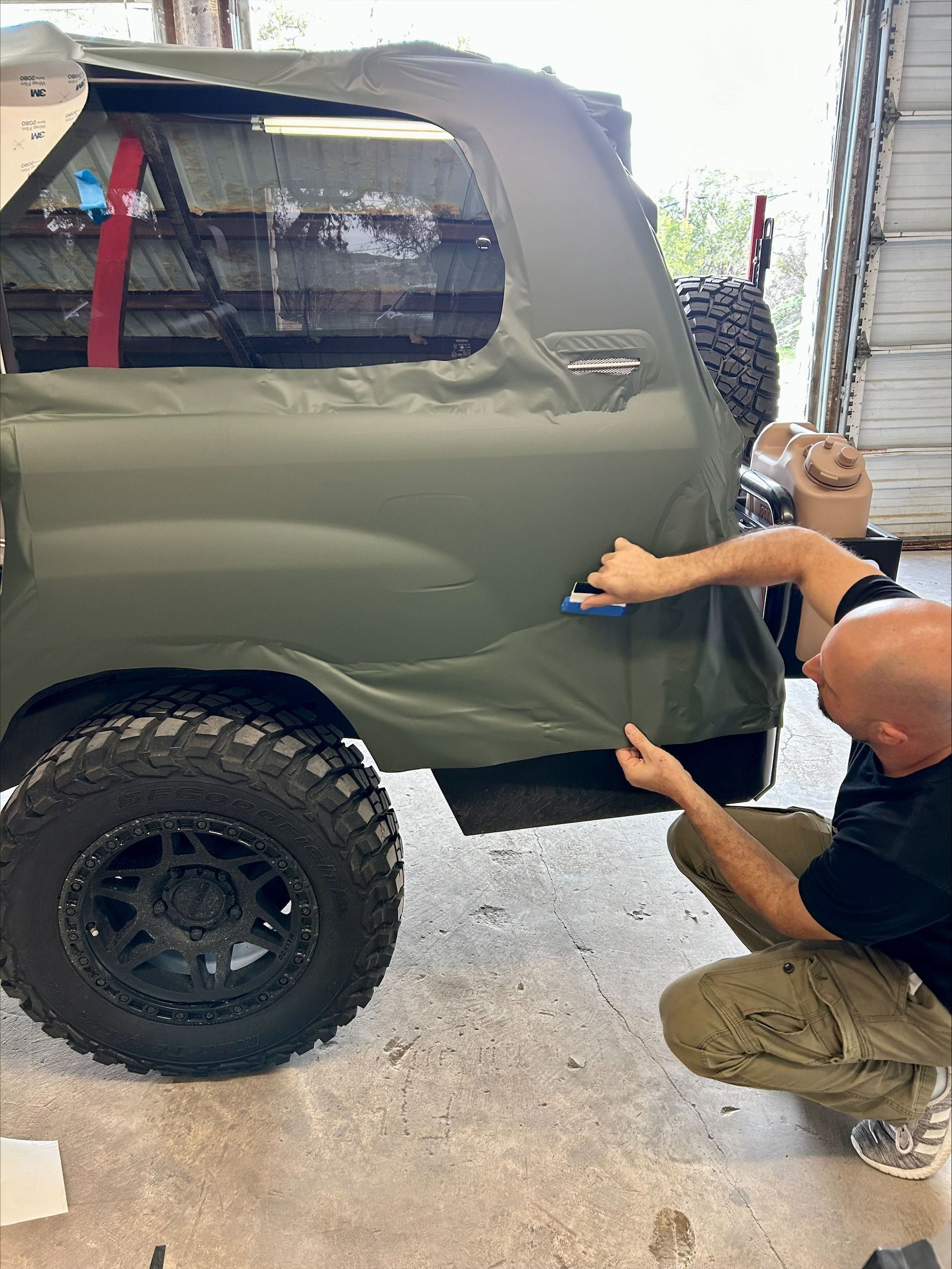 Close-up of a white sports car hood with a black stripe and a Corvette emblem. The hood has a prominent vent.