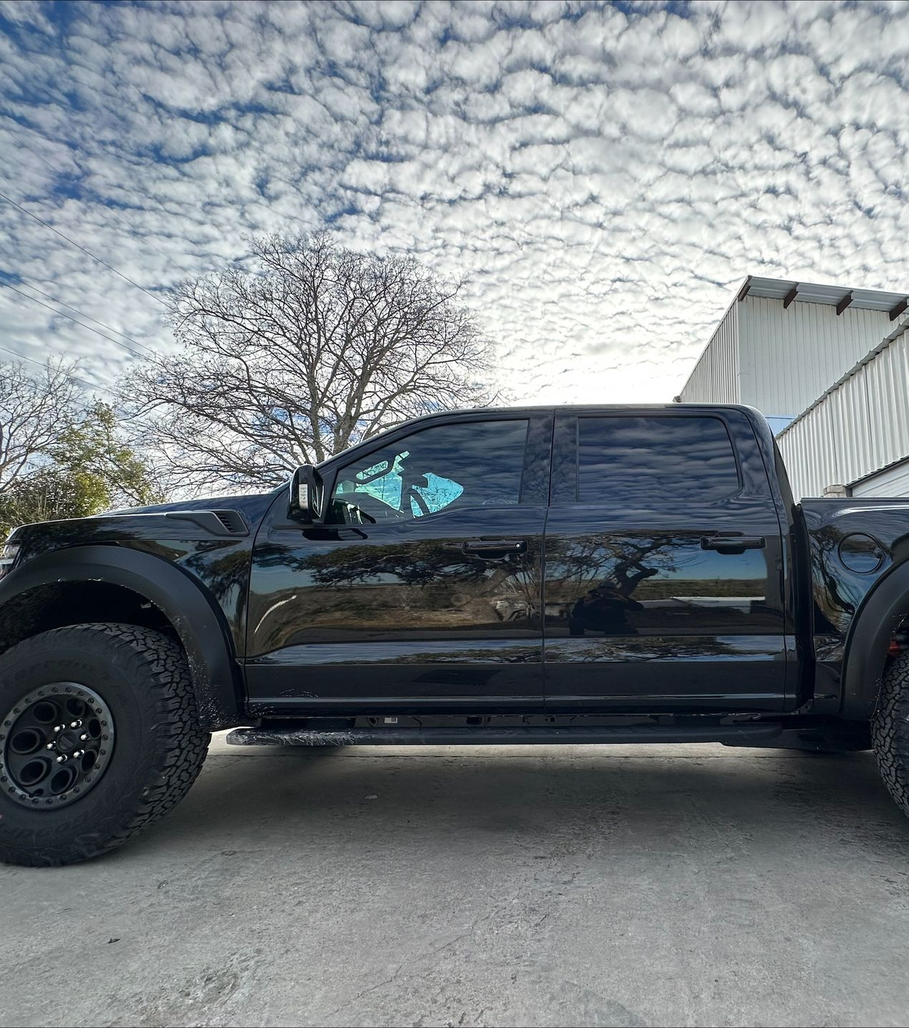 Black Ford Raptor truck parked outdoors under a cloudy sky.