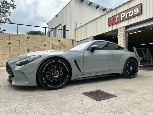 White lifted pickup truck with visible rust on the bed, parked in front of a building on a sunny day.