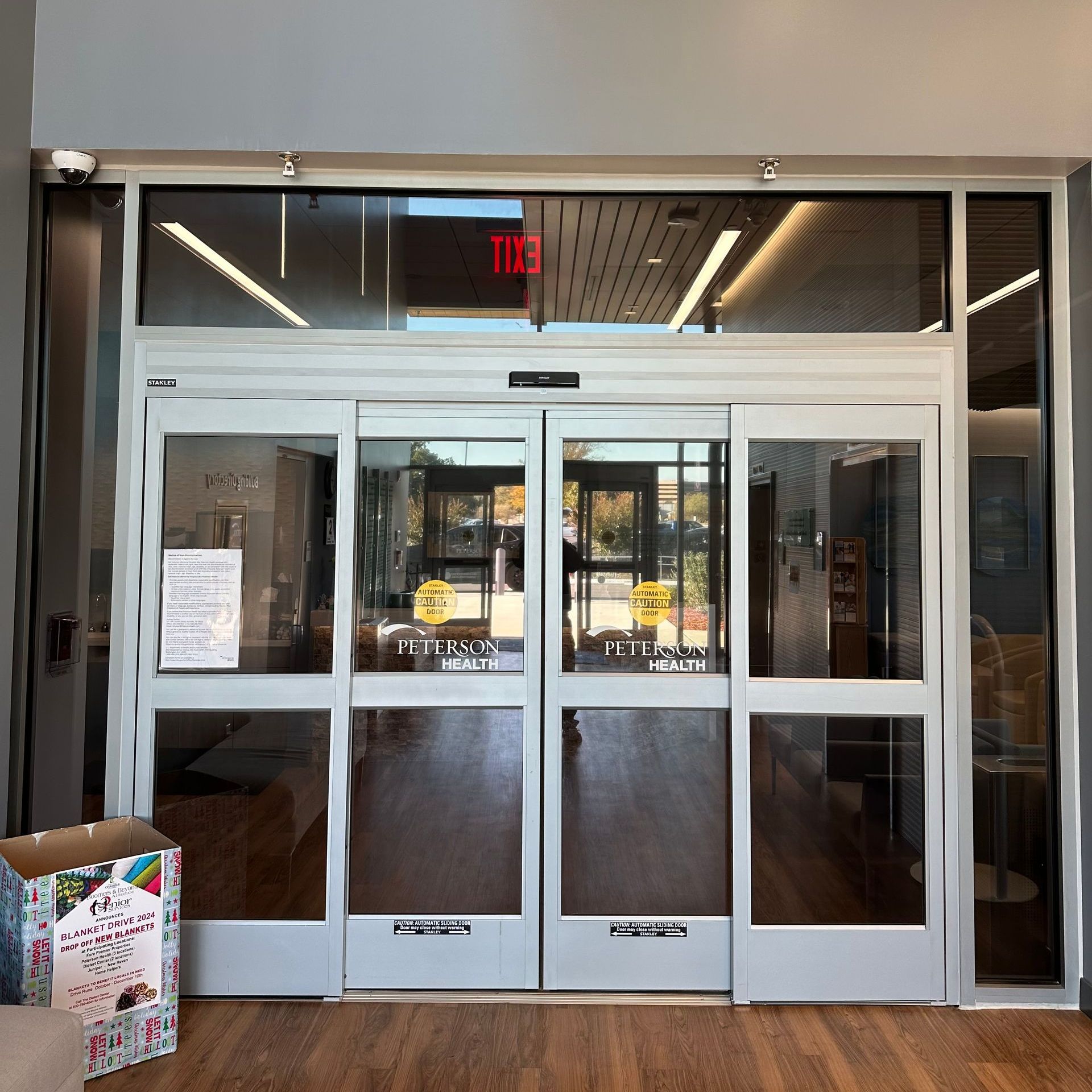 Automatic sliding glass doors at a building entrance with a gift box on the floor.