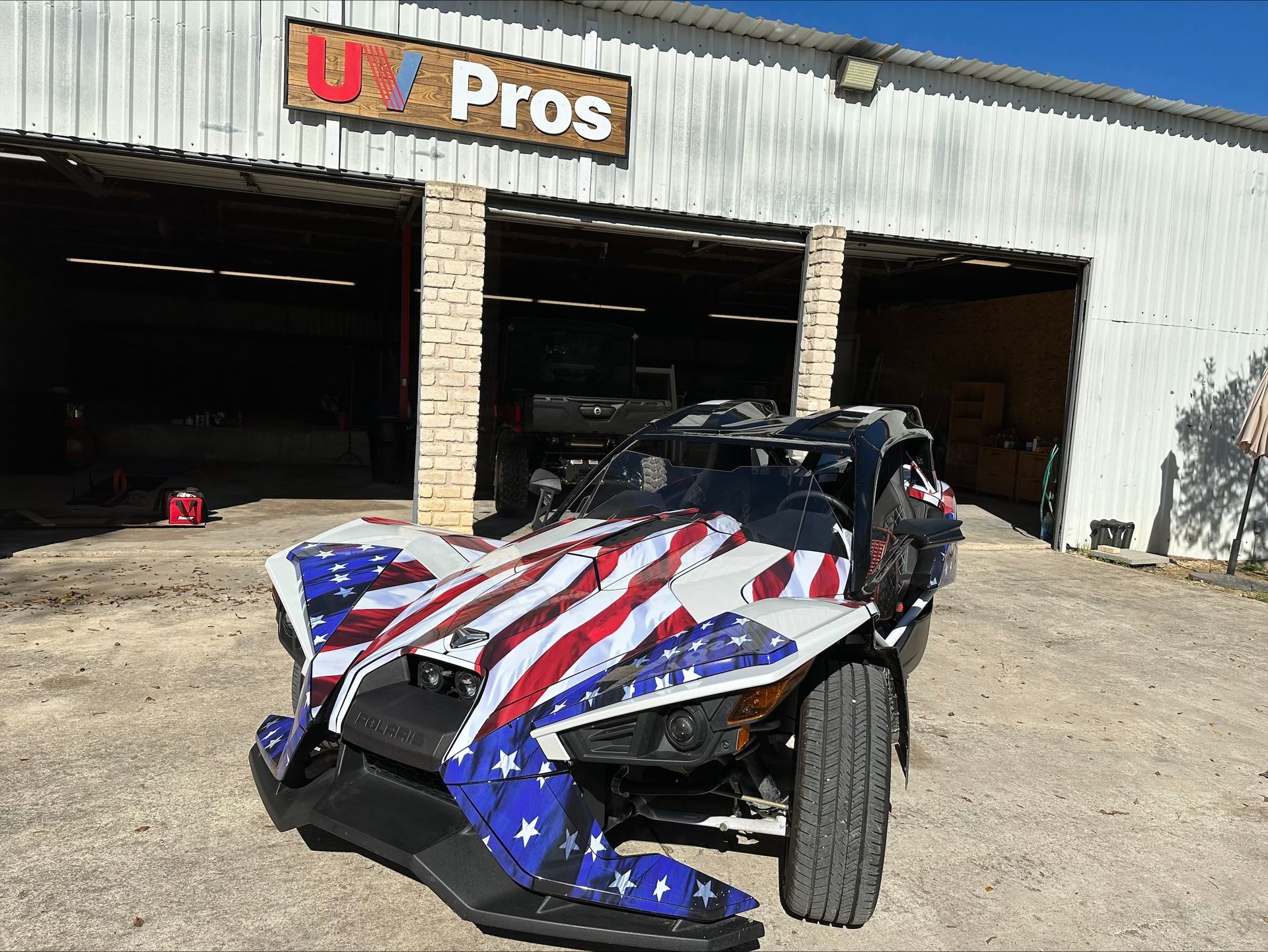 A collection of colorful trophies displayed on a wooden surface in front of a wooden wall.