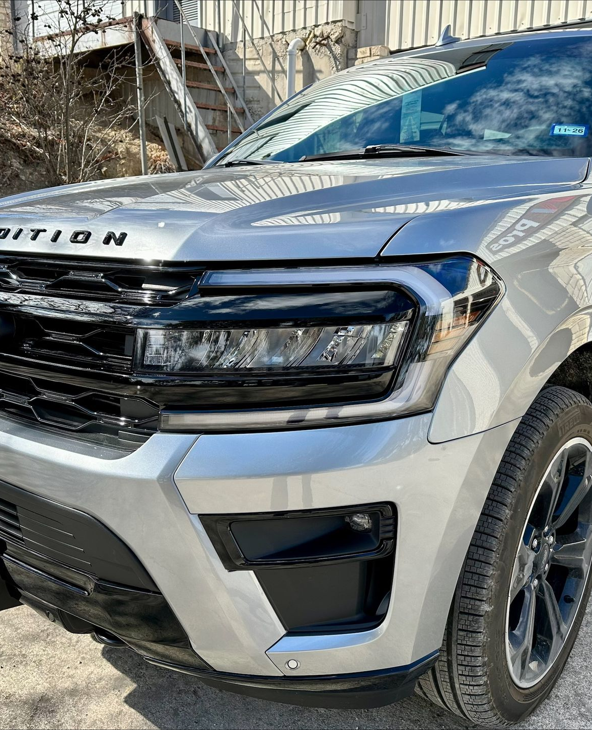 Silver Ford Expedition SUV. Black grill, headlights, and bumper.
