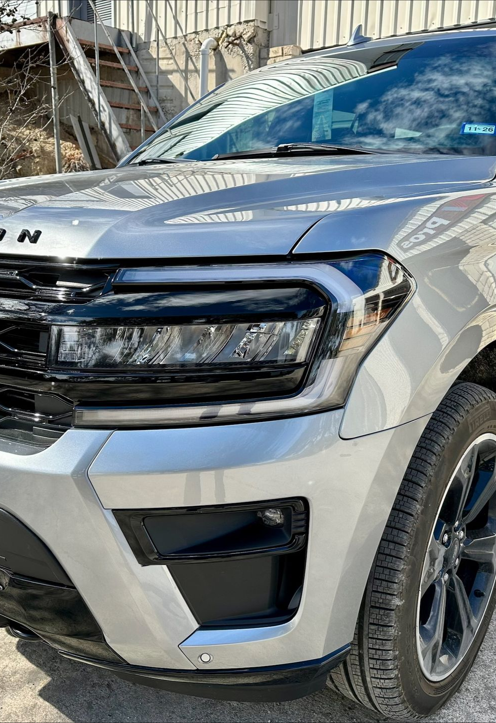 White pickup truck door undergoing repair, with rust visible on the lower section. The open door reveals a partially finished body work and primer.