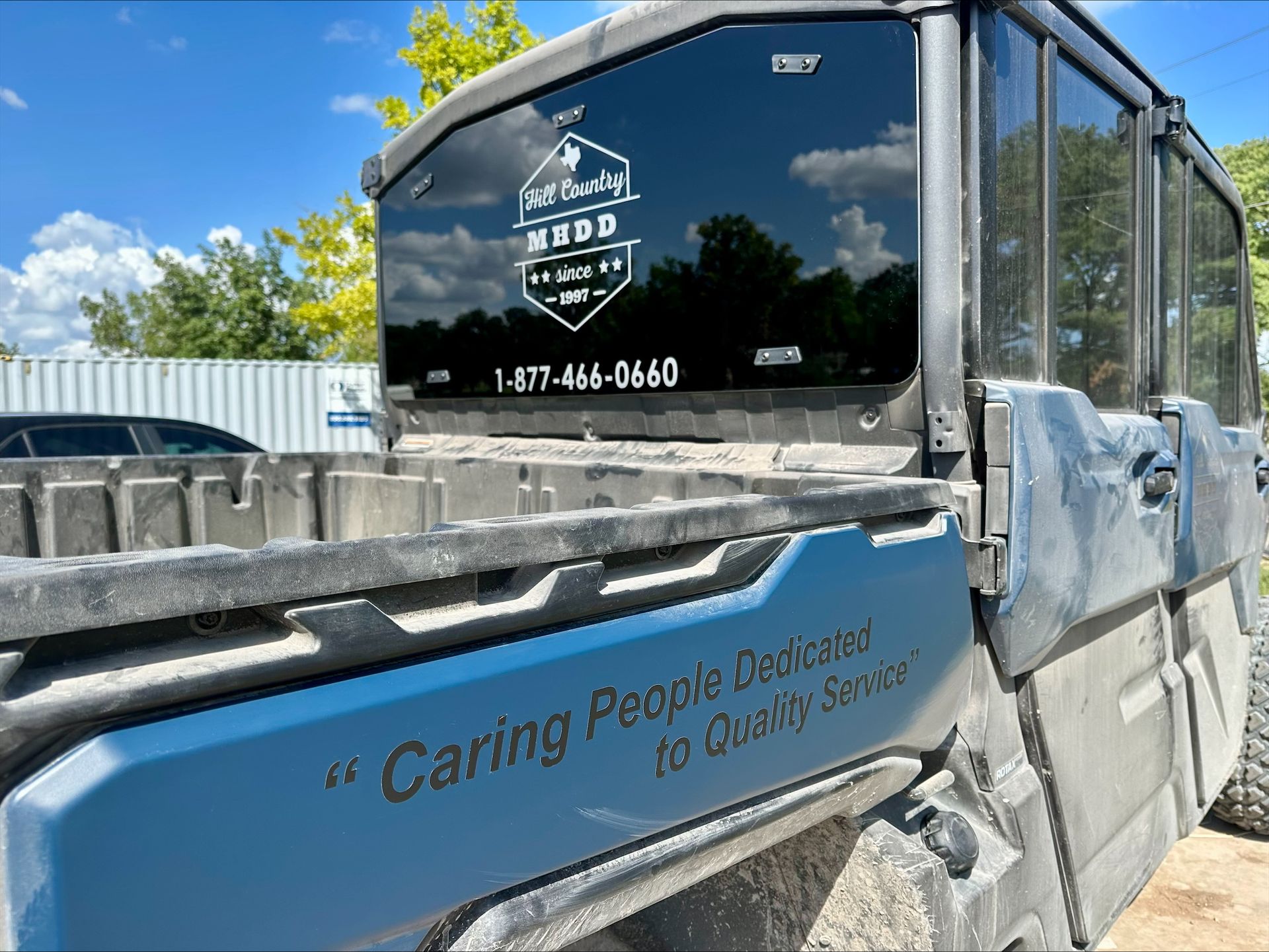 Blue utility vehicle with tinted windows, logo on rear, and text: 