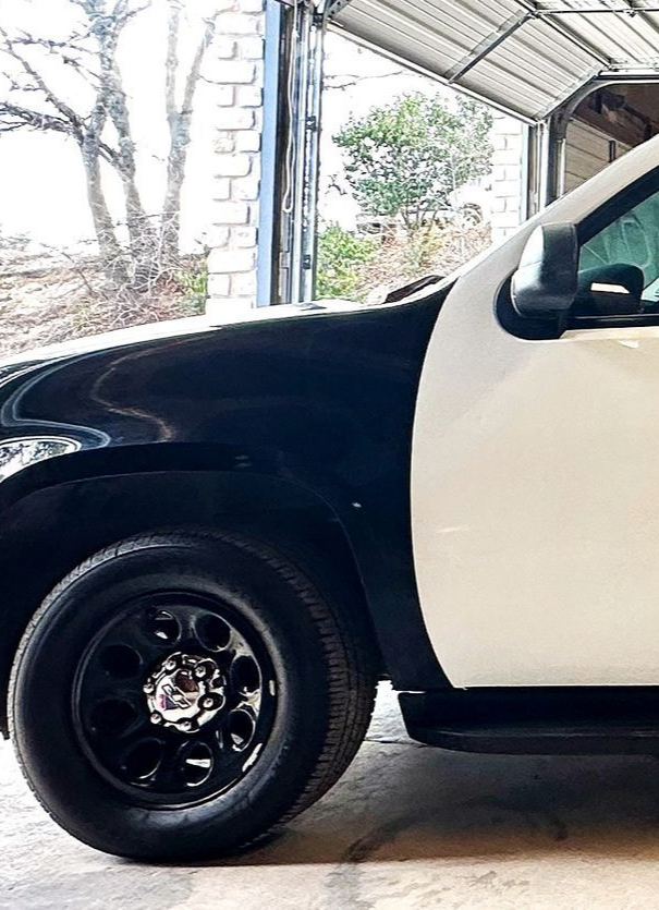Black and white police car parked inside a garage, with black wheels.