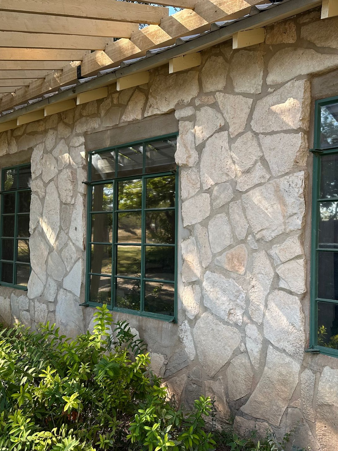 Man on a ladder installing window film, violin on floor, arms outstretched.