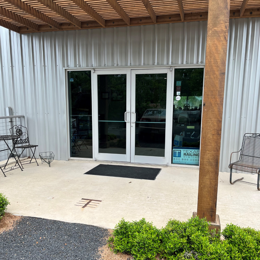 Man looking out large windows in a living room with a brown couch, lamps, and a small table. The outside view is of trees and hills.