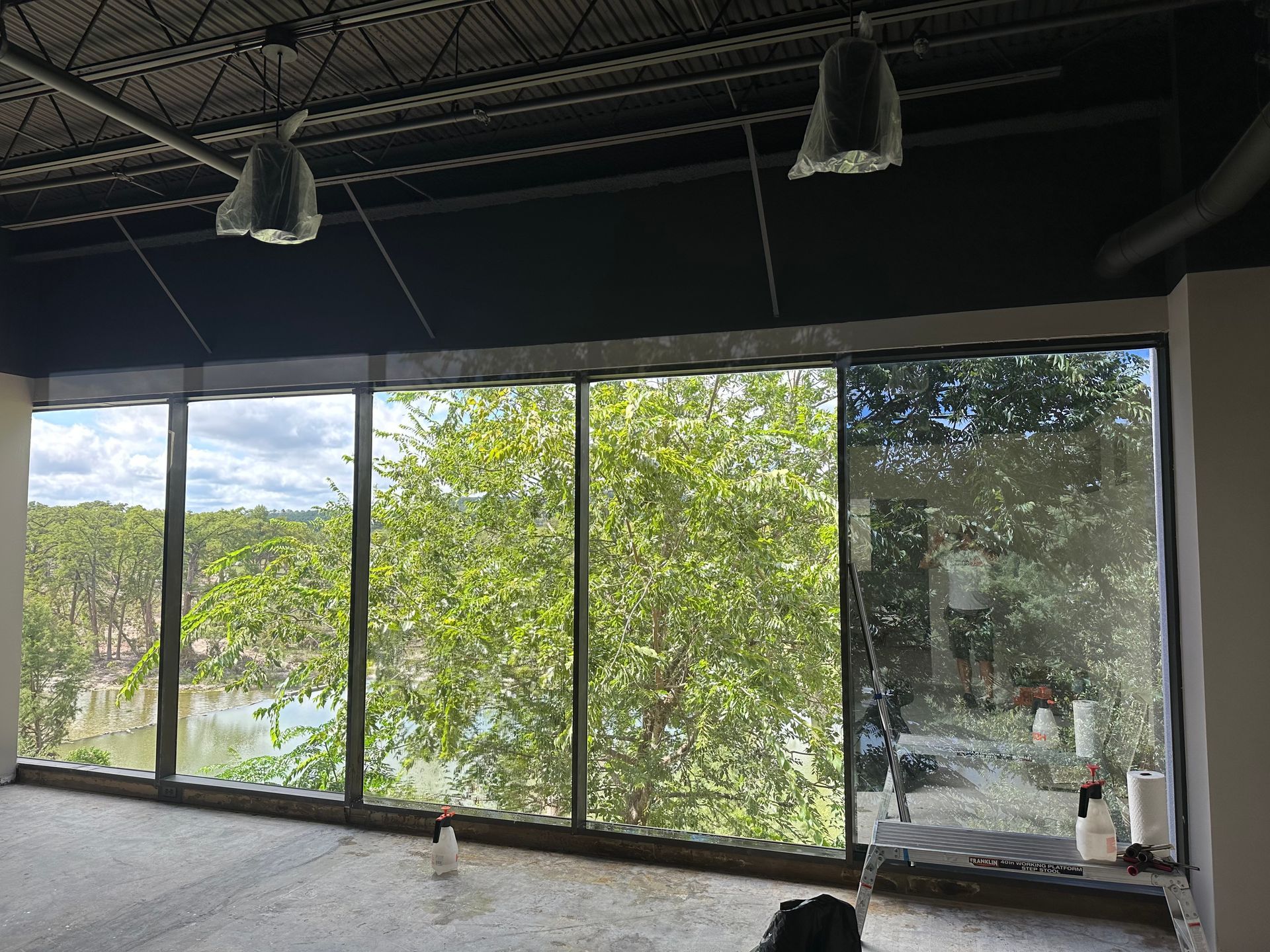 Storefront with large windows, gray siding, stone accents, and a blue metal roof under a twilight sky.