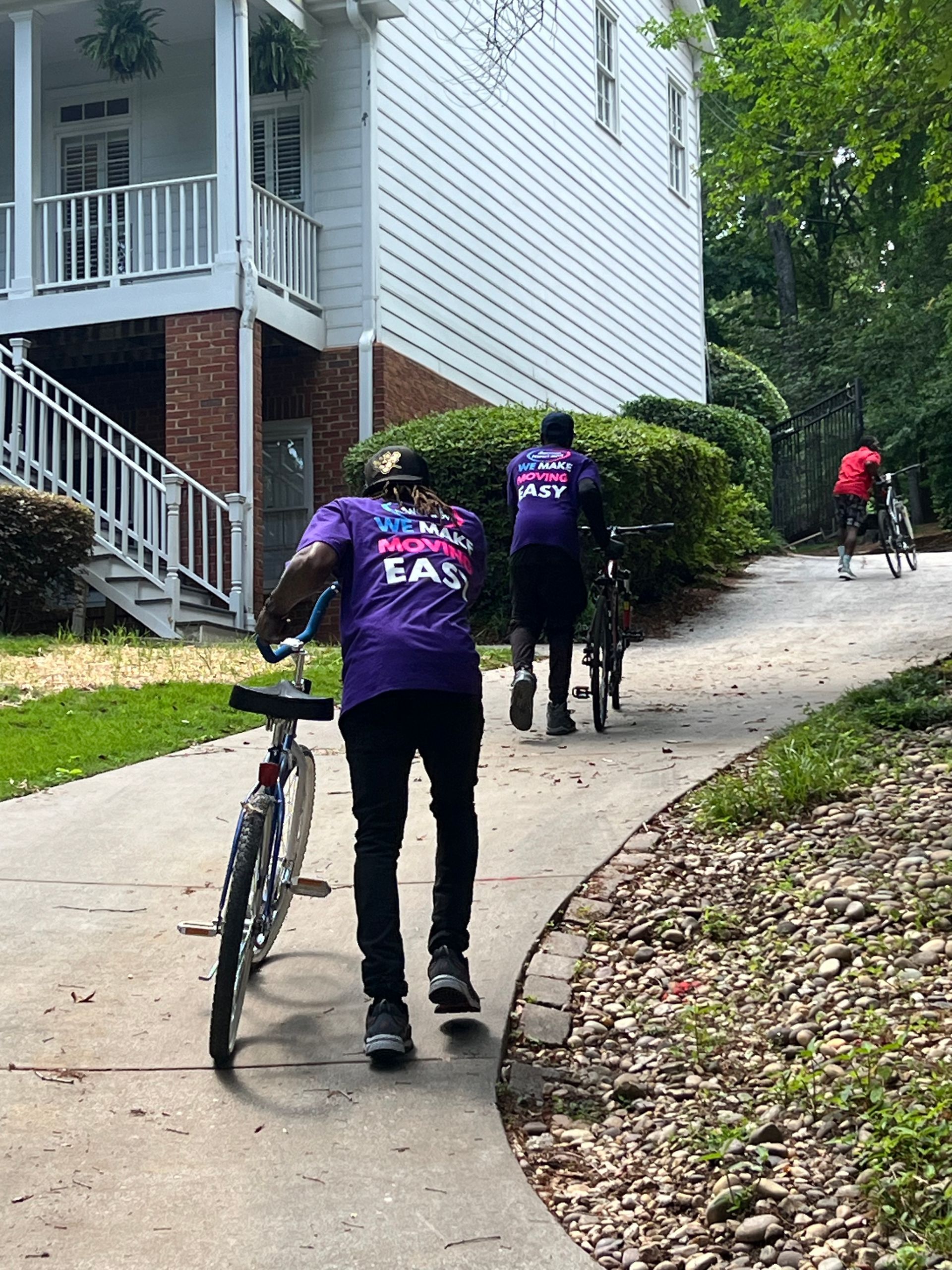 A man in a purple shirt is riding a bike down a sidewalk.