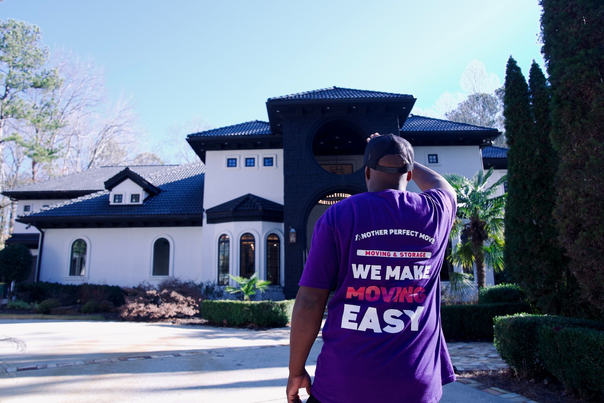 A man wearing a purple shirt that says we make moving easy