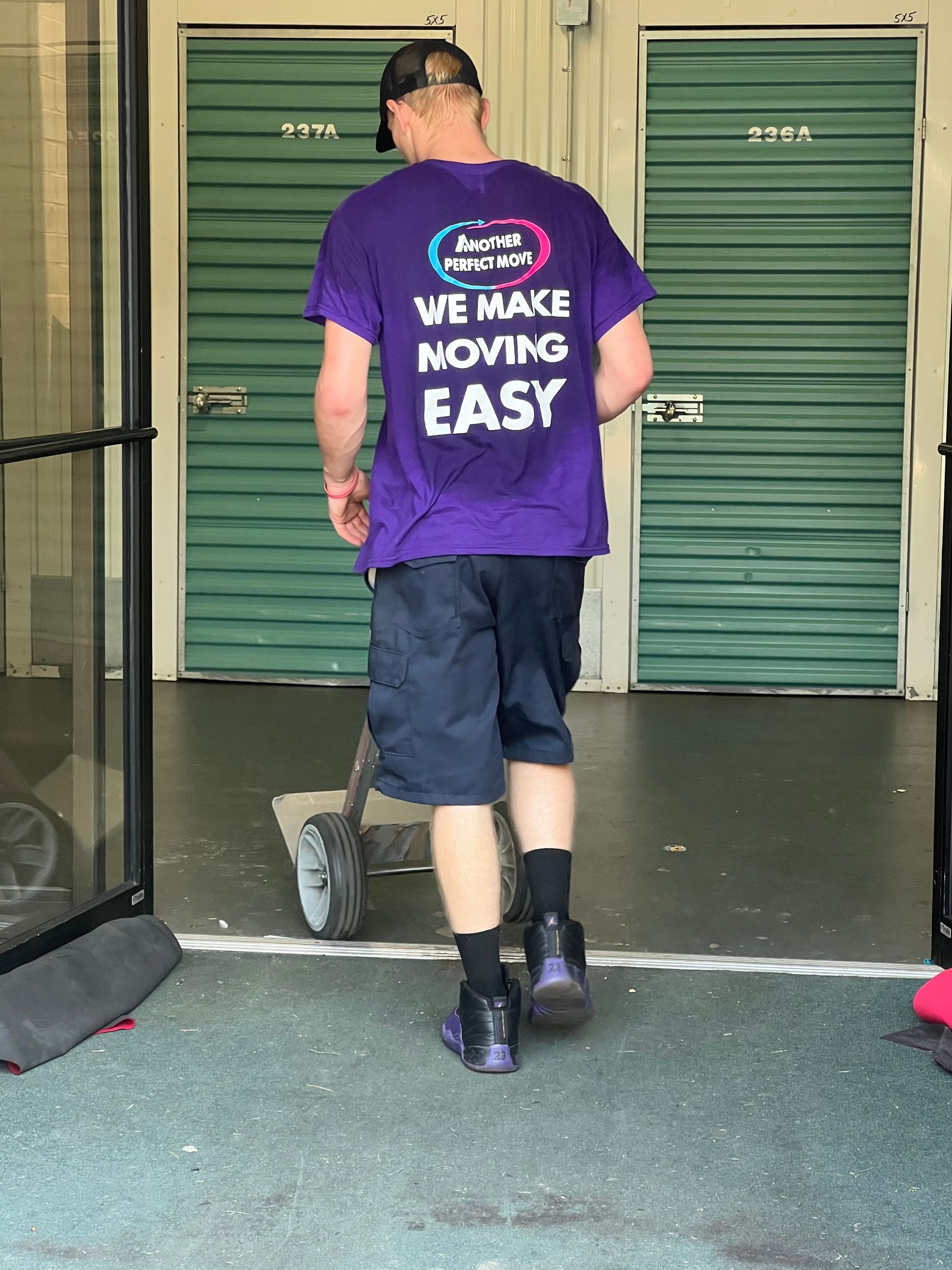 A man wearing a purple shirt that says we make moving easy