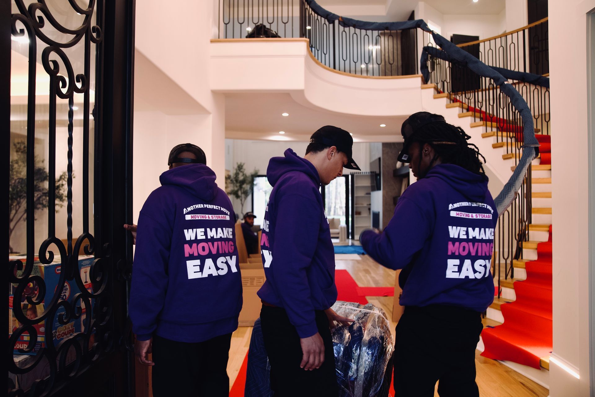 Three men wearing purple hoodies that say we make moving easy