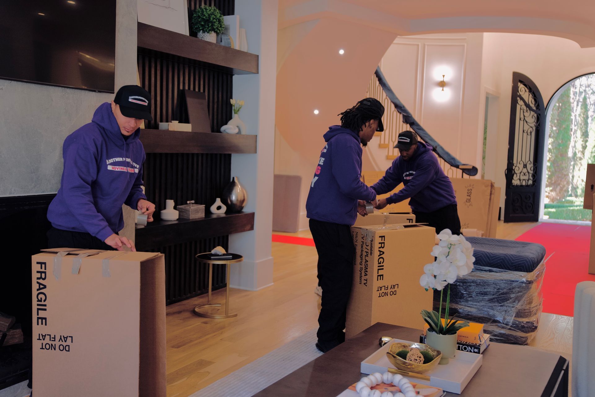A group of people are packing boxes in a living room.