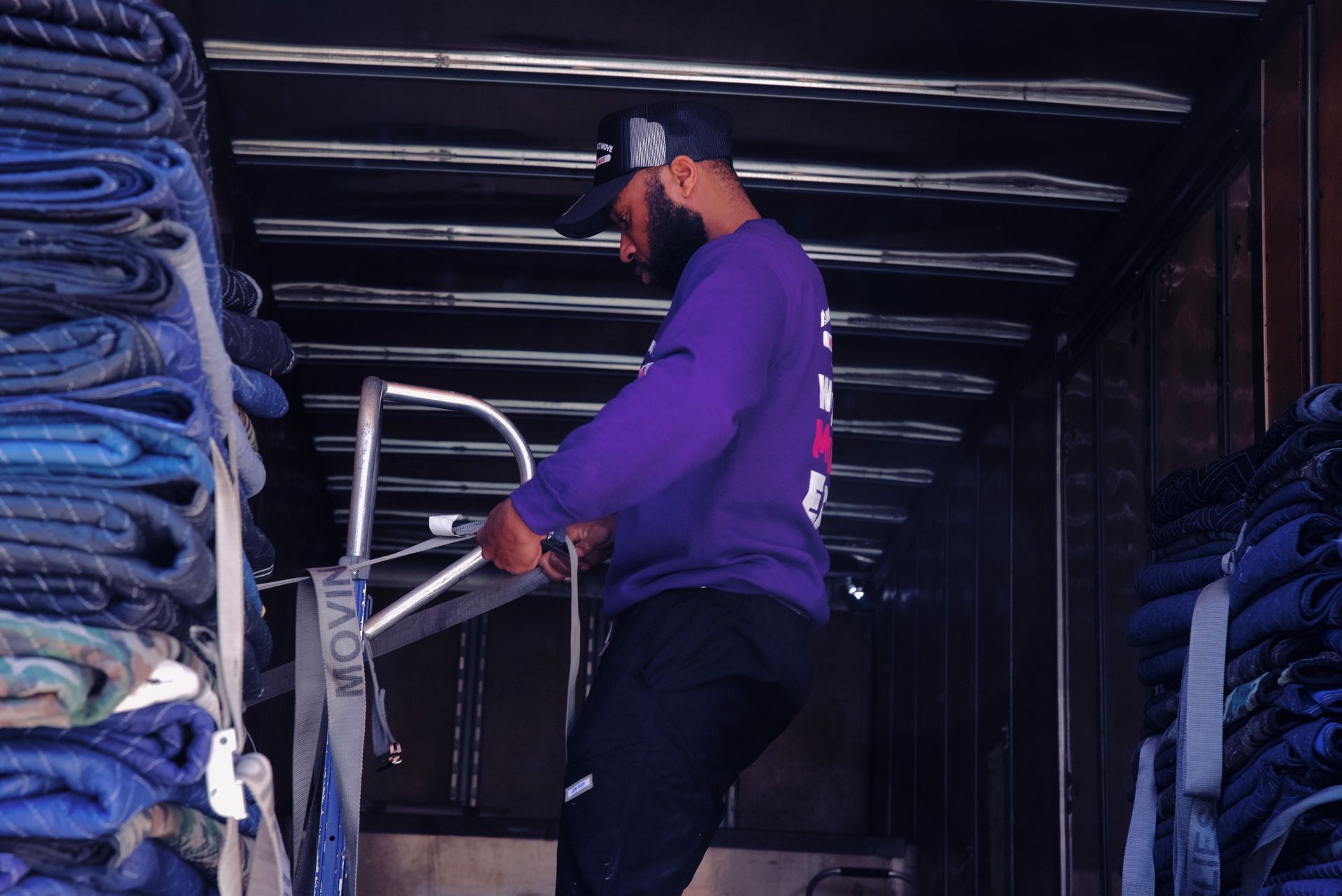 A man in a purple shirt is standing on a ladder in a truck.