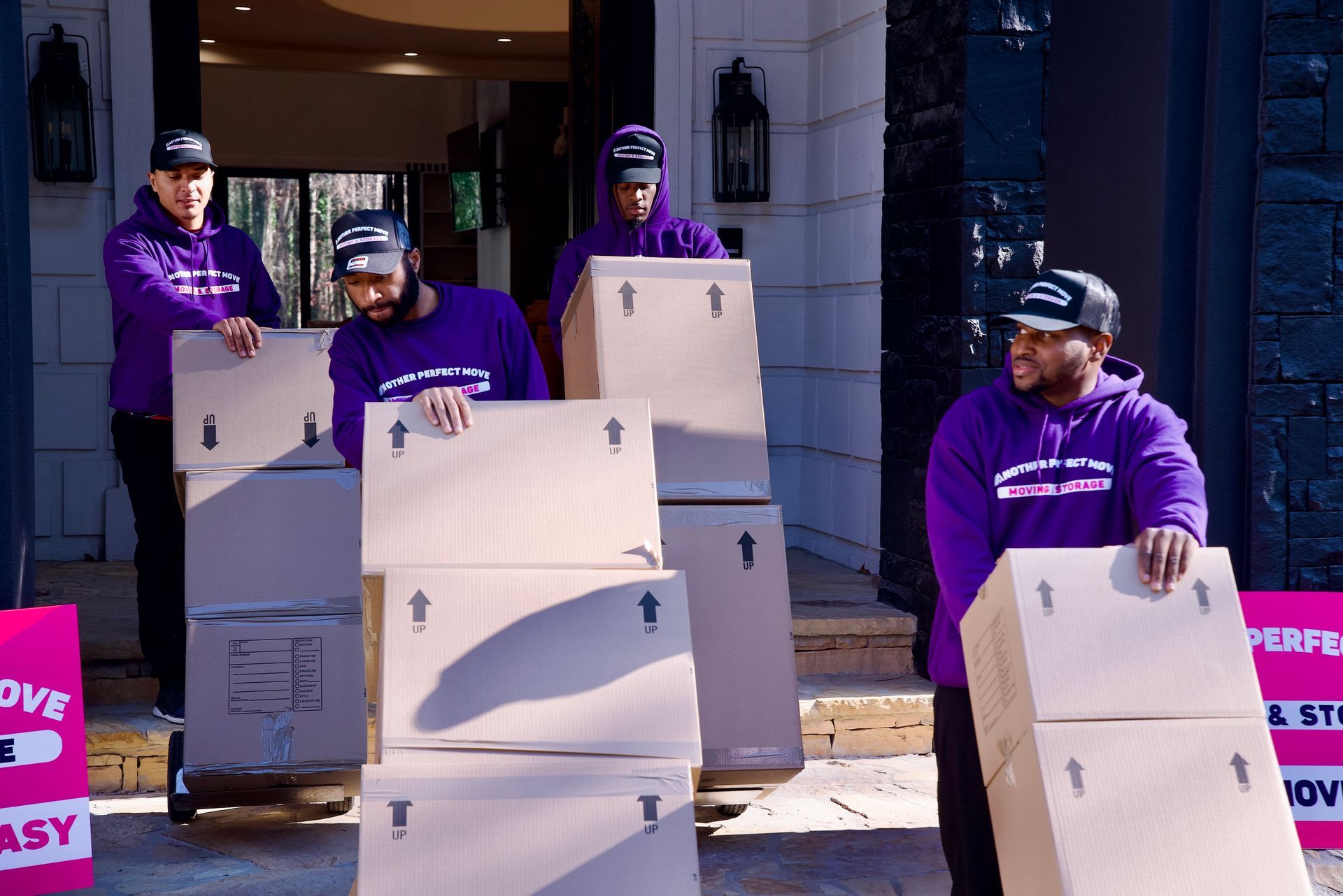 A group of men are carrying boxes in front of a house.