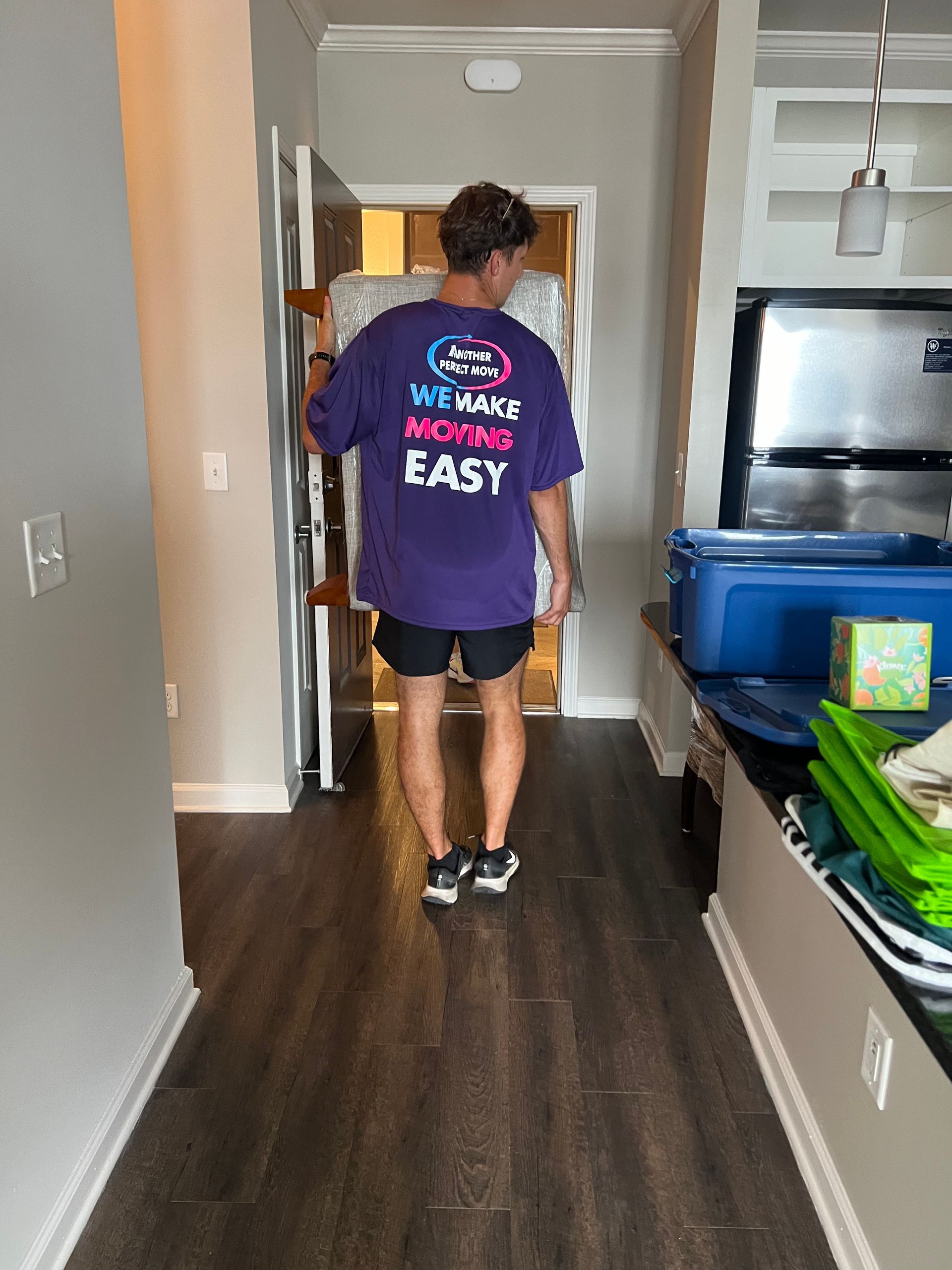 A man in a purple shirt is standing in a hallway.