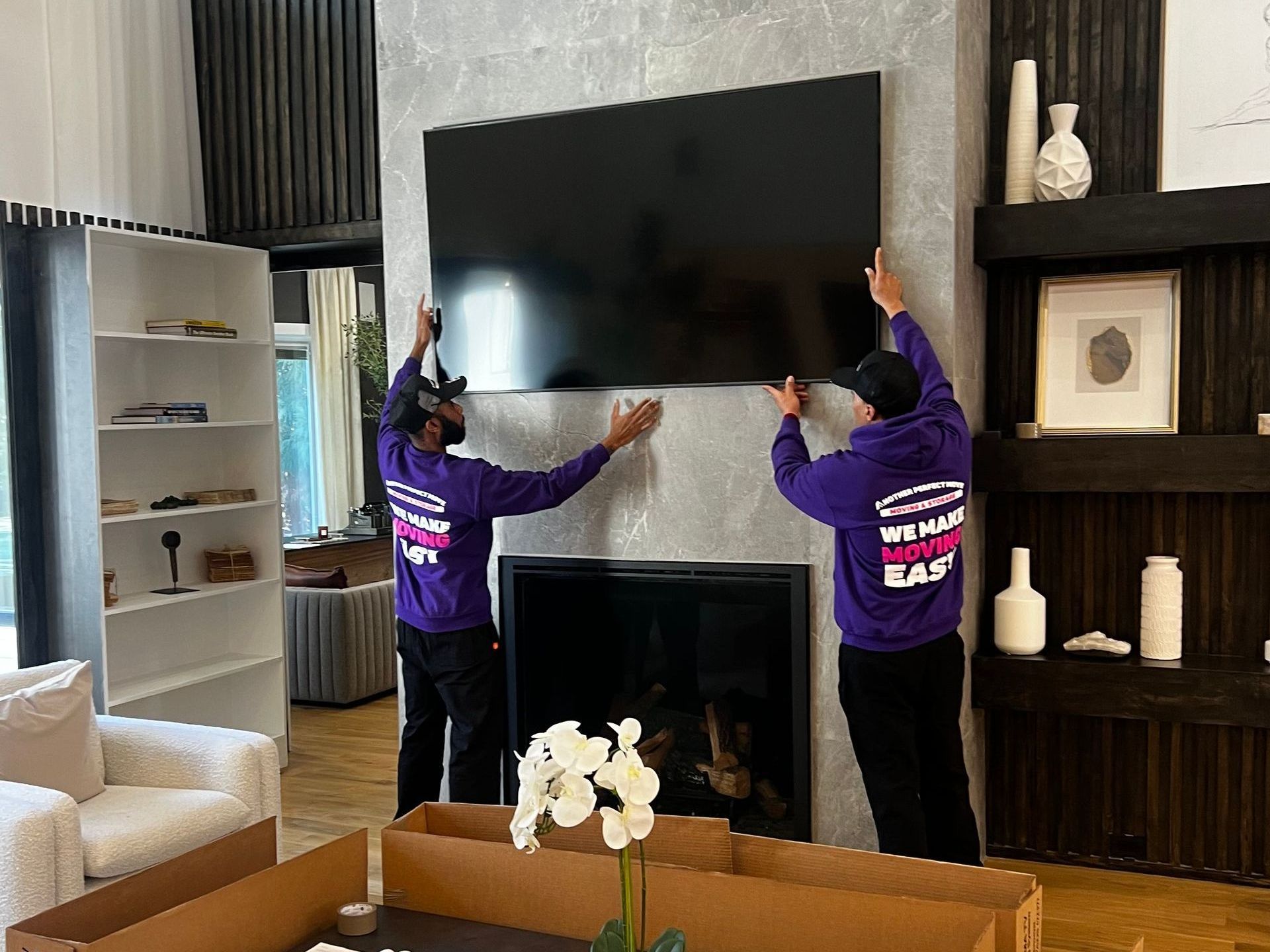 Two men are installing a flat screen tv on the wall in a living room.
