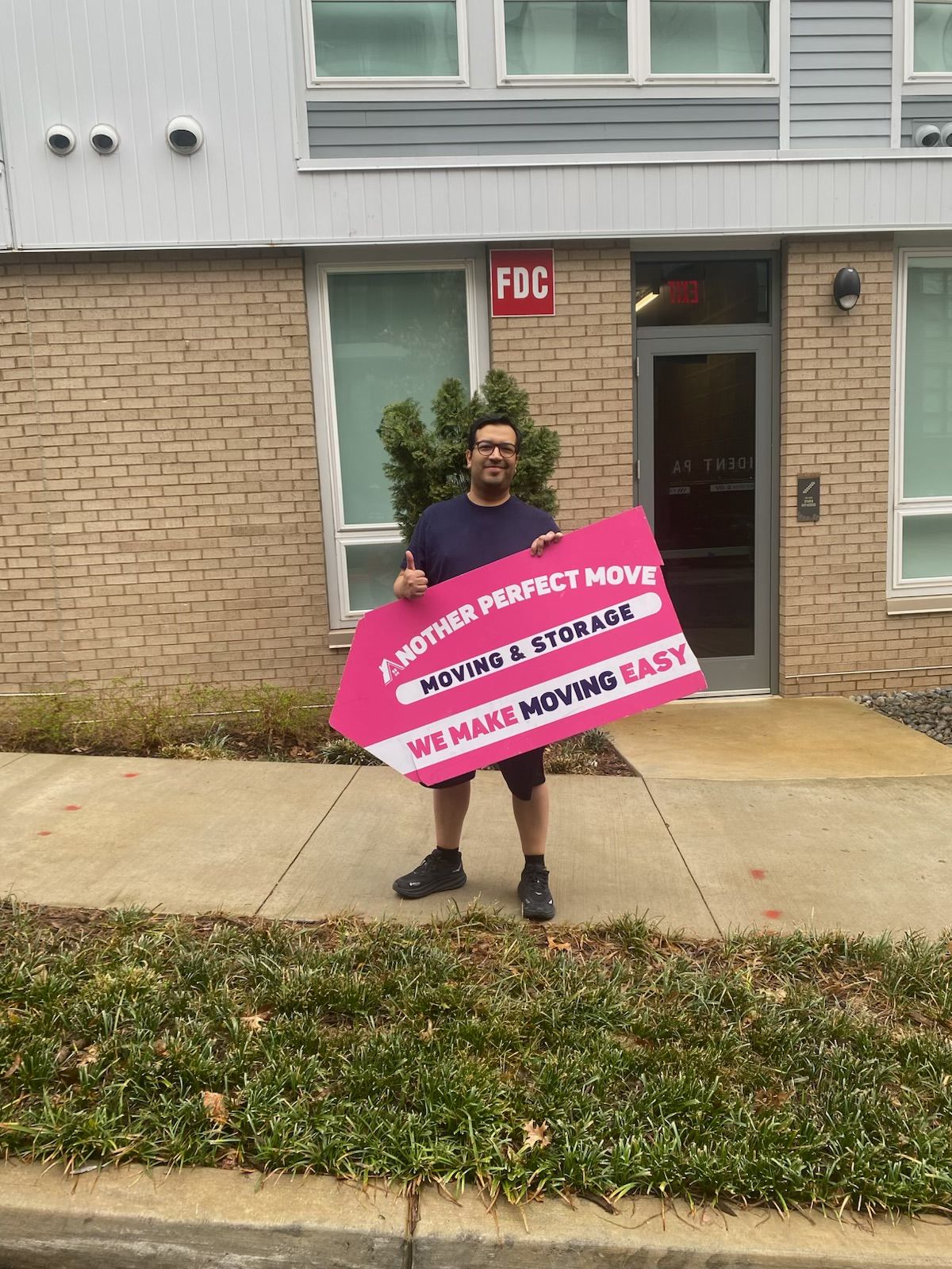 A man is holding a sign in front of a brick building.