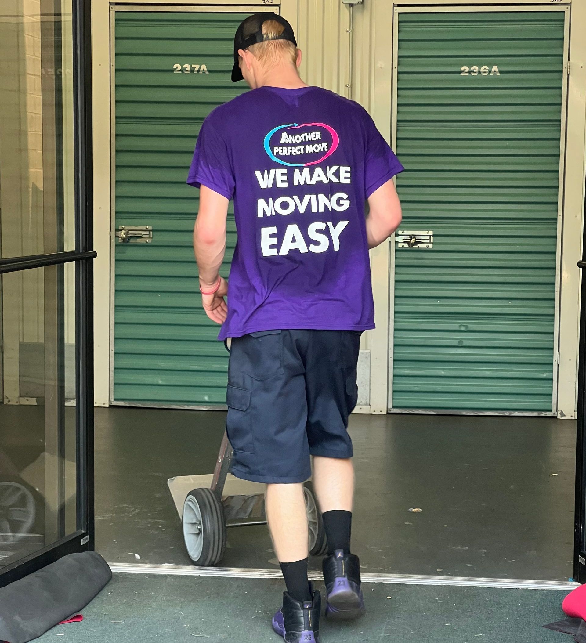 A man wearing a purple shirt that says we make moving easy