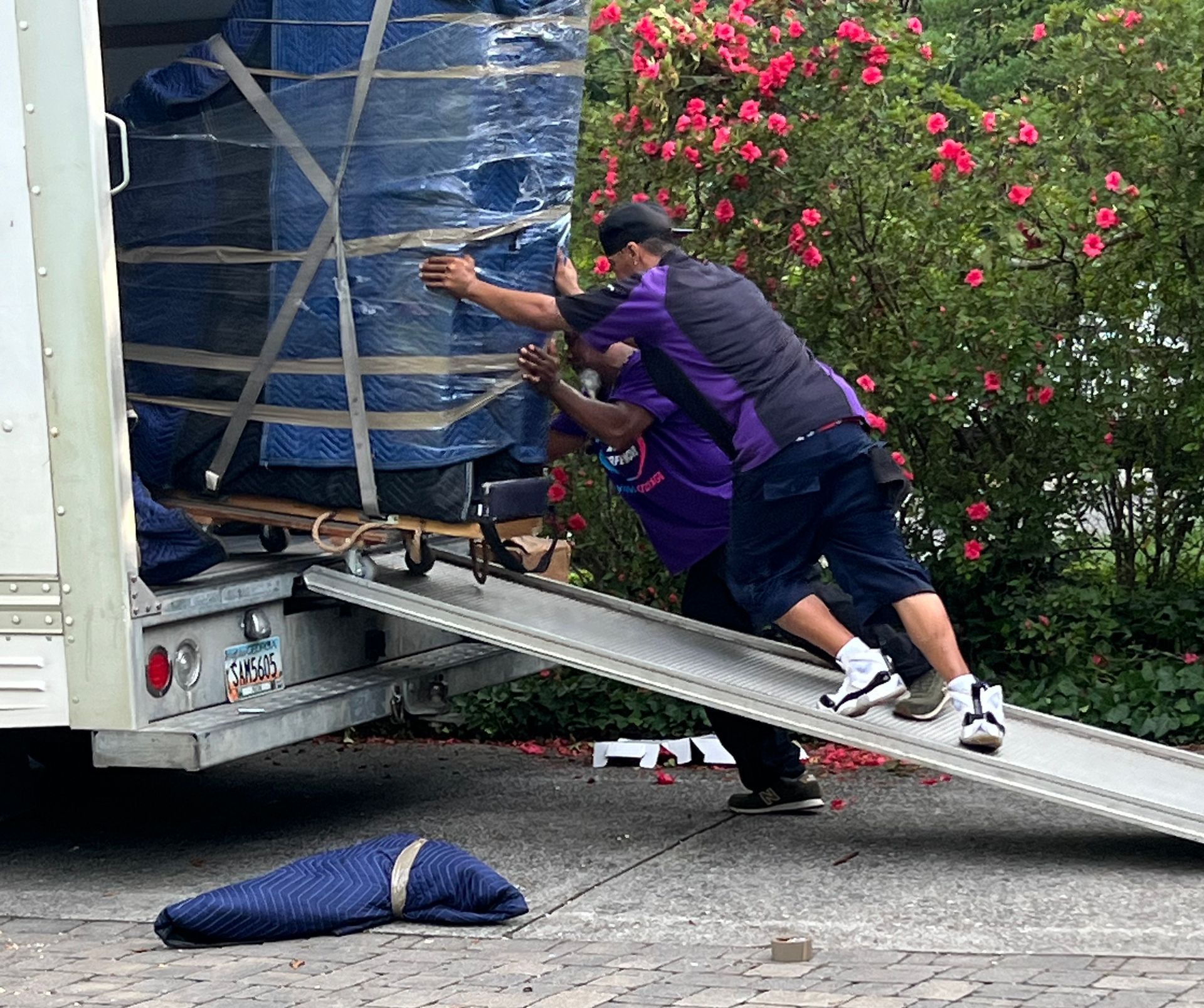 A group of men are loading a piano into a moving truck.