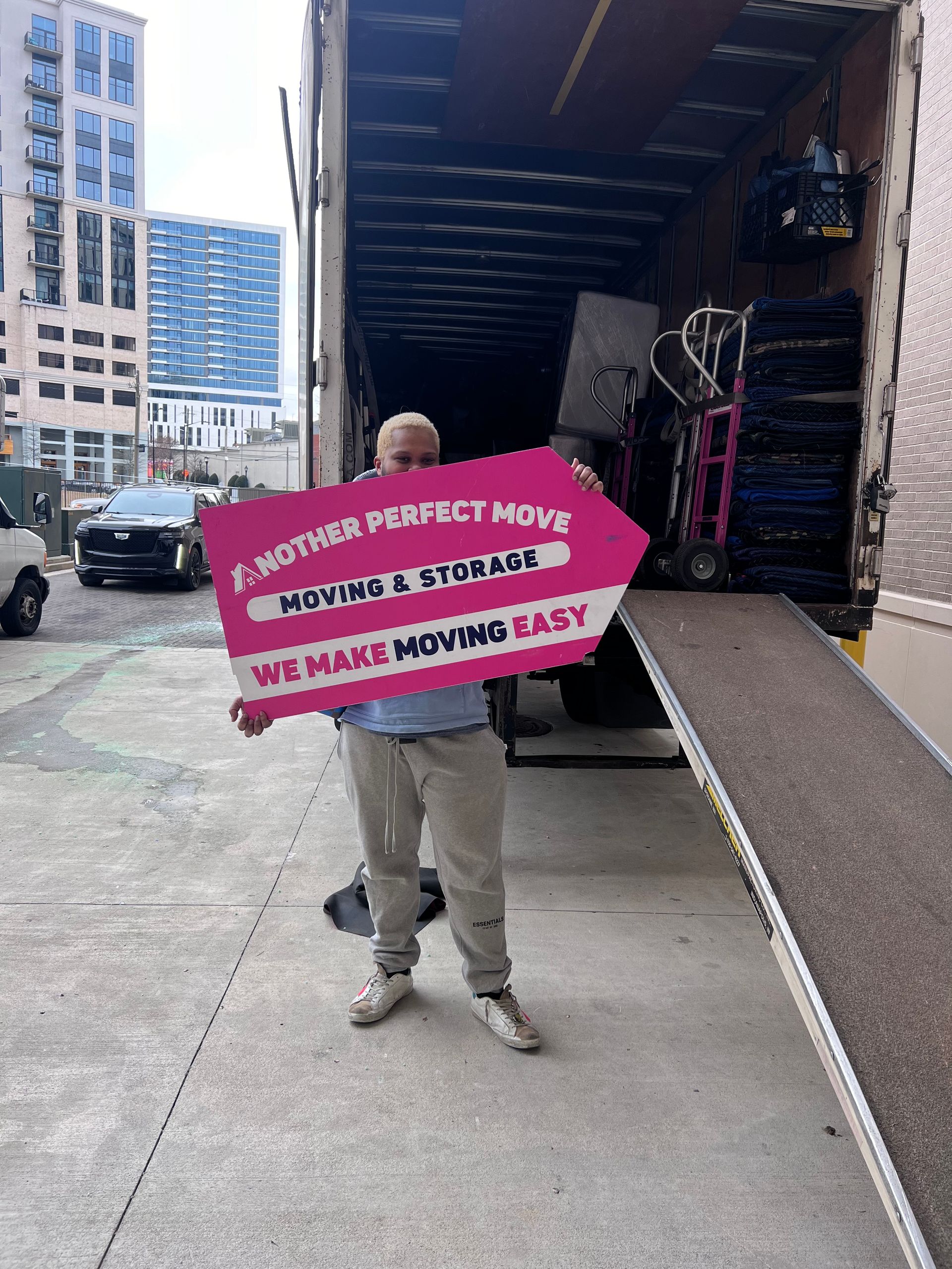 A man is holding a sign in front of a moving truck.