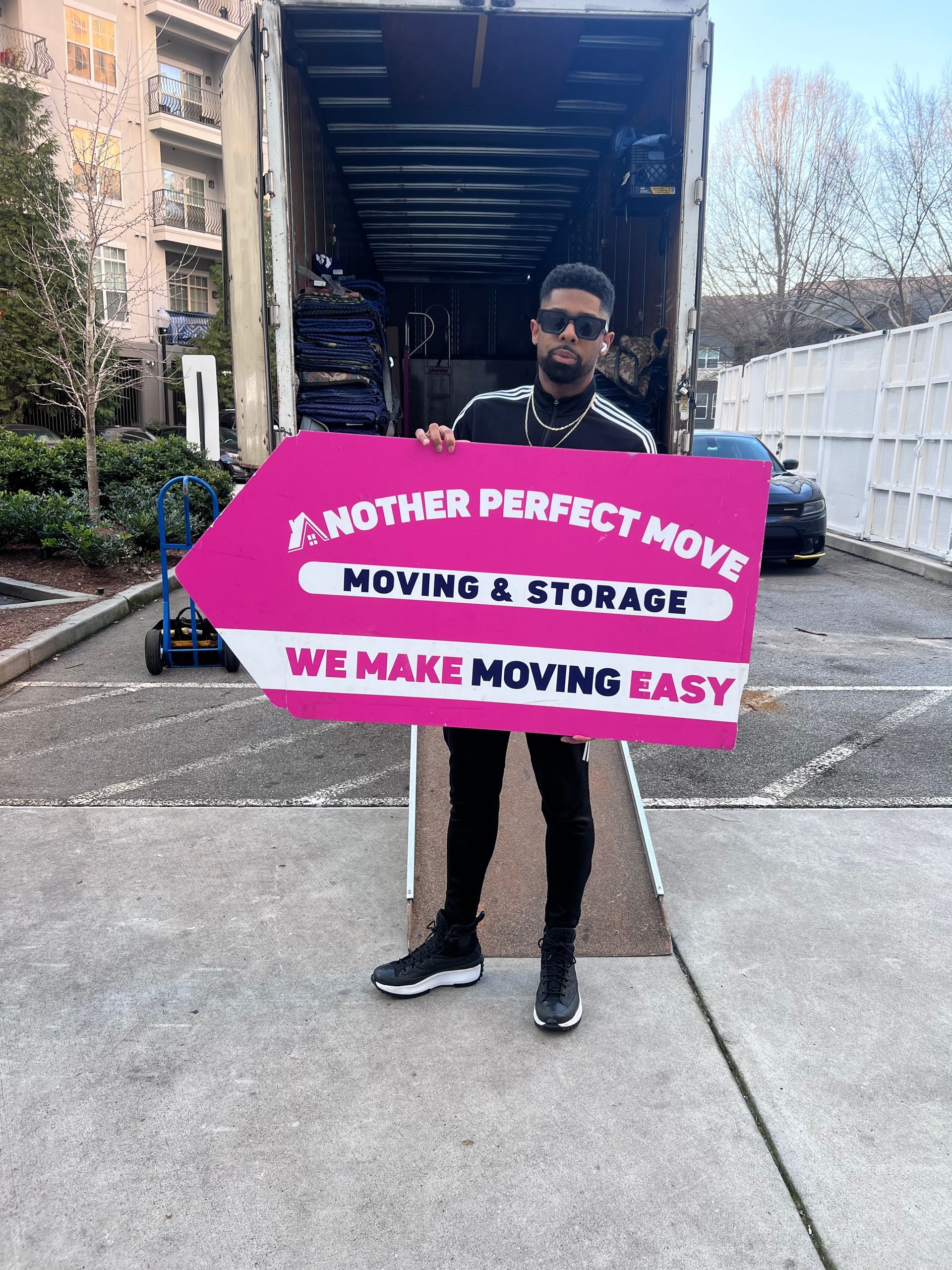 A man is holding a sign that says `` another perfect move moving & storage we make moving easy ''.
