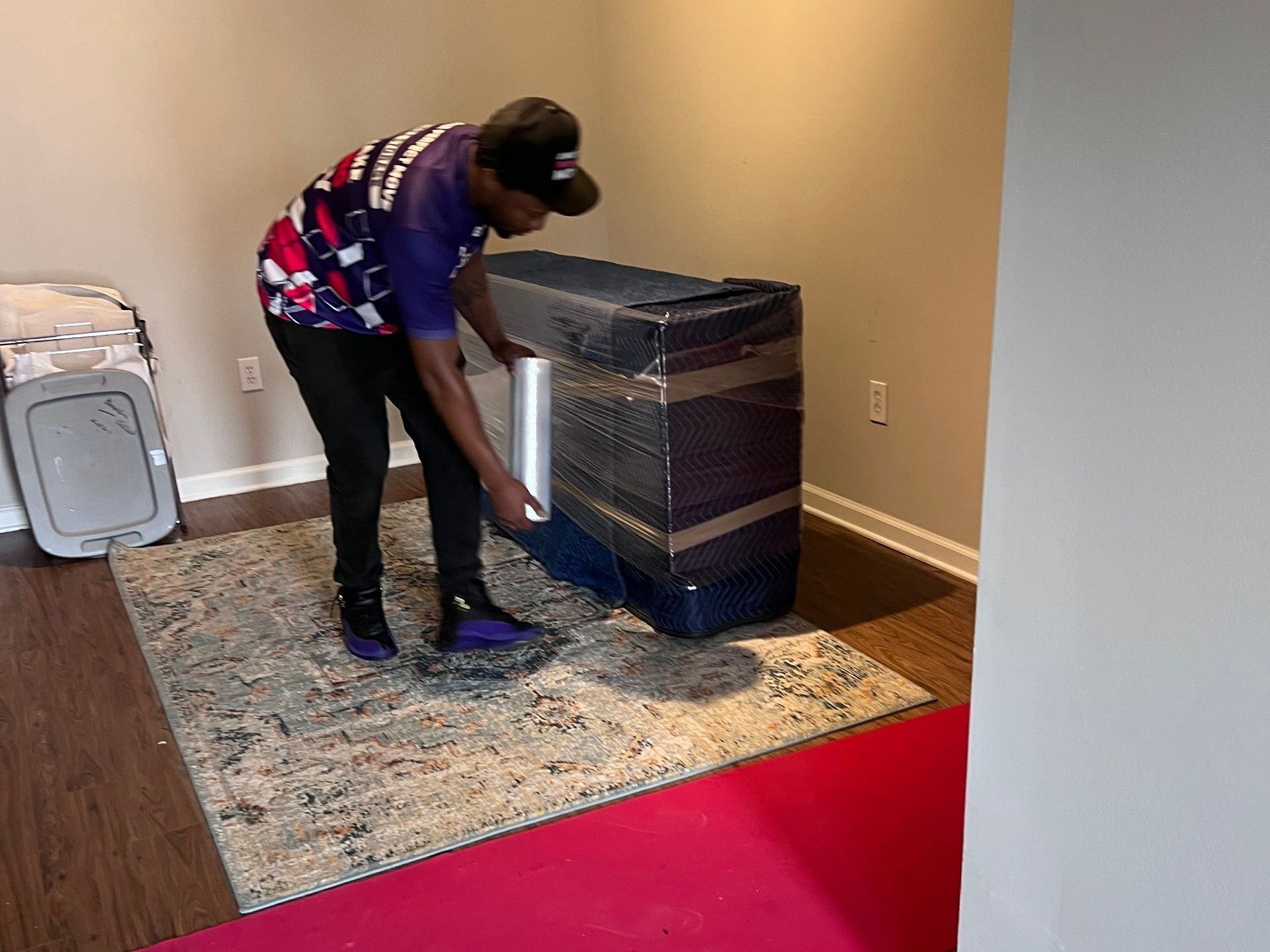 A man is standing next to a box wrapped in plastic in a living room.