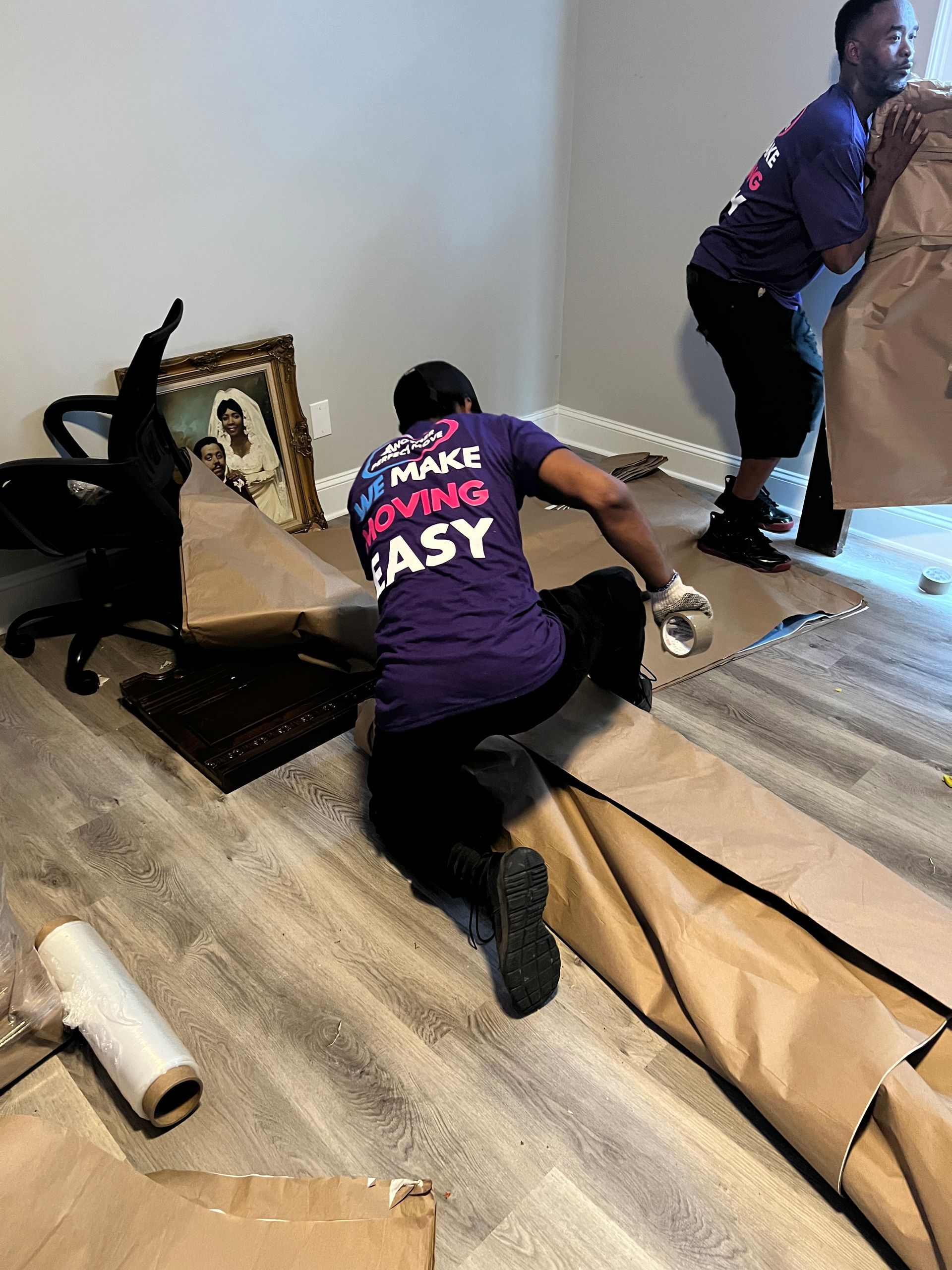 A man in a purple shirt is kneeling down in a living room.