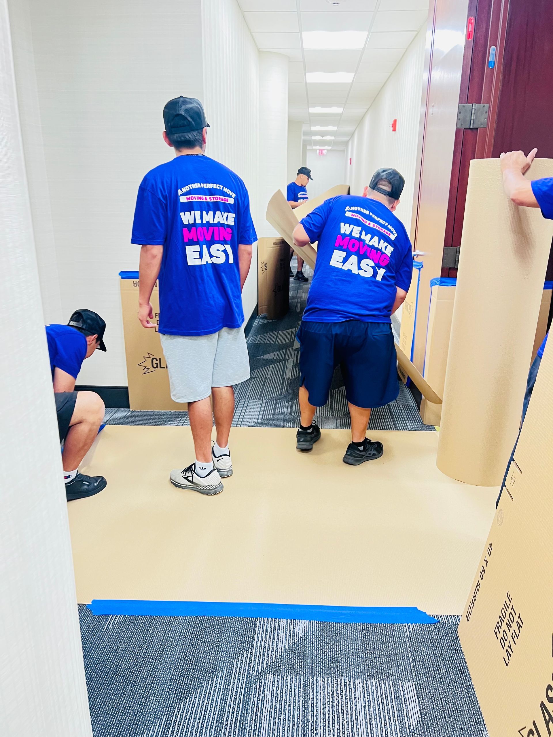 A group of men are moving boxes in a hallway.