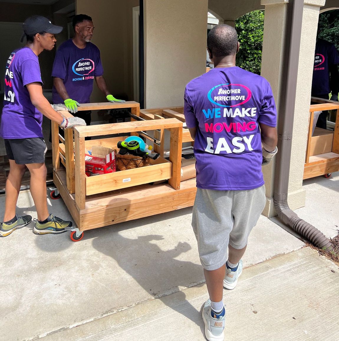 A man wearing a purple shirt that says `` we make it easy '' is standing in front of a building.