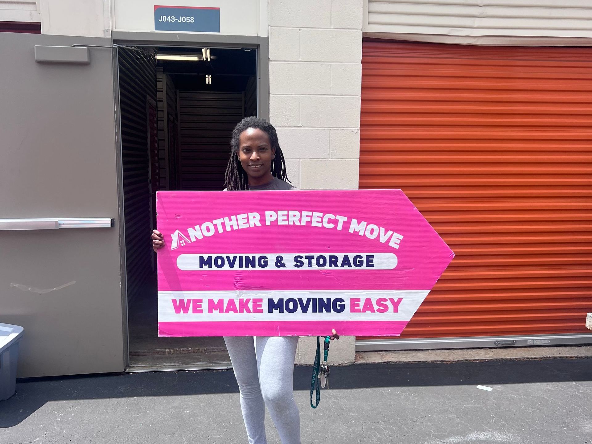 A woman is holding a sign that says `` another perfect move moving & storage we make moving easy ''.