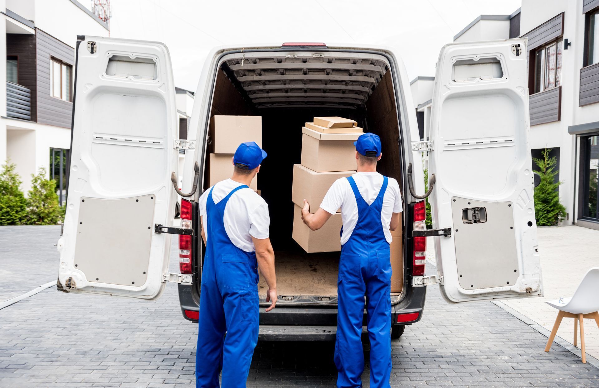 Two movers are loading boxes into a van.