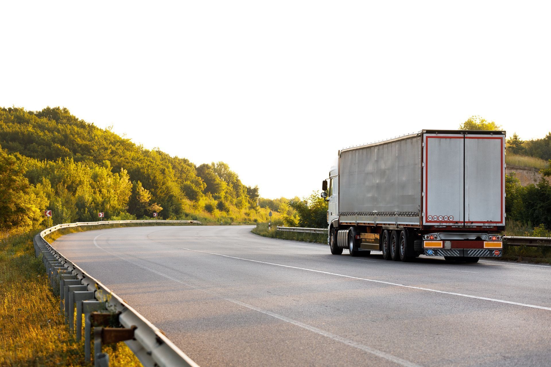 A white semi truck is driving down a curvy highway.