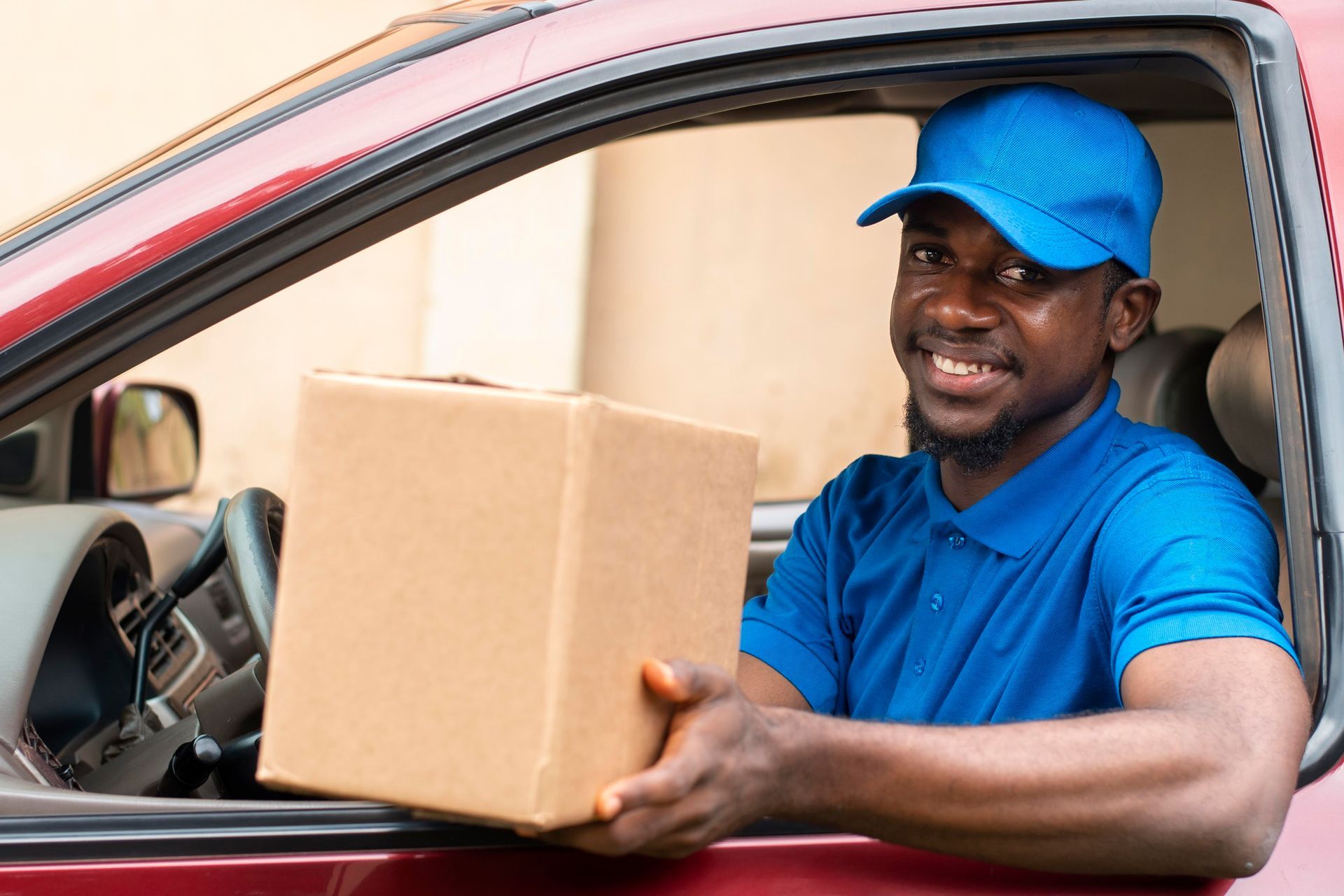 A delivery man is sitting in a car holding a cardboard box.