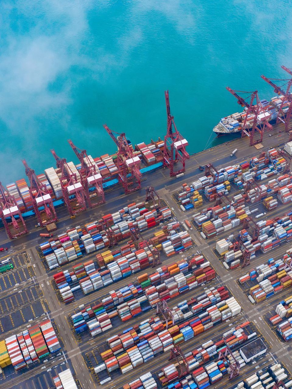 An aerial view of a port filled with lots of containers and cranes.