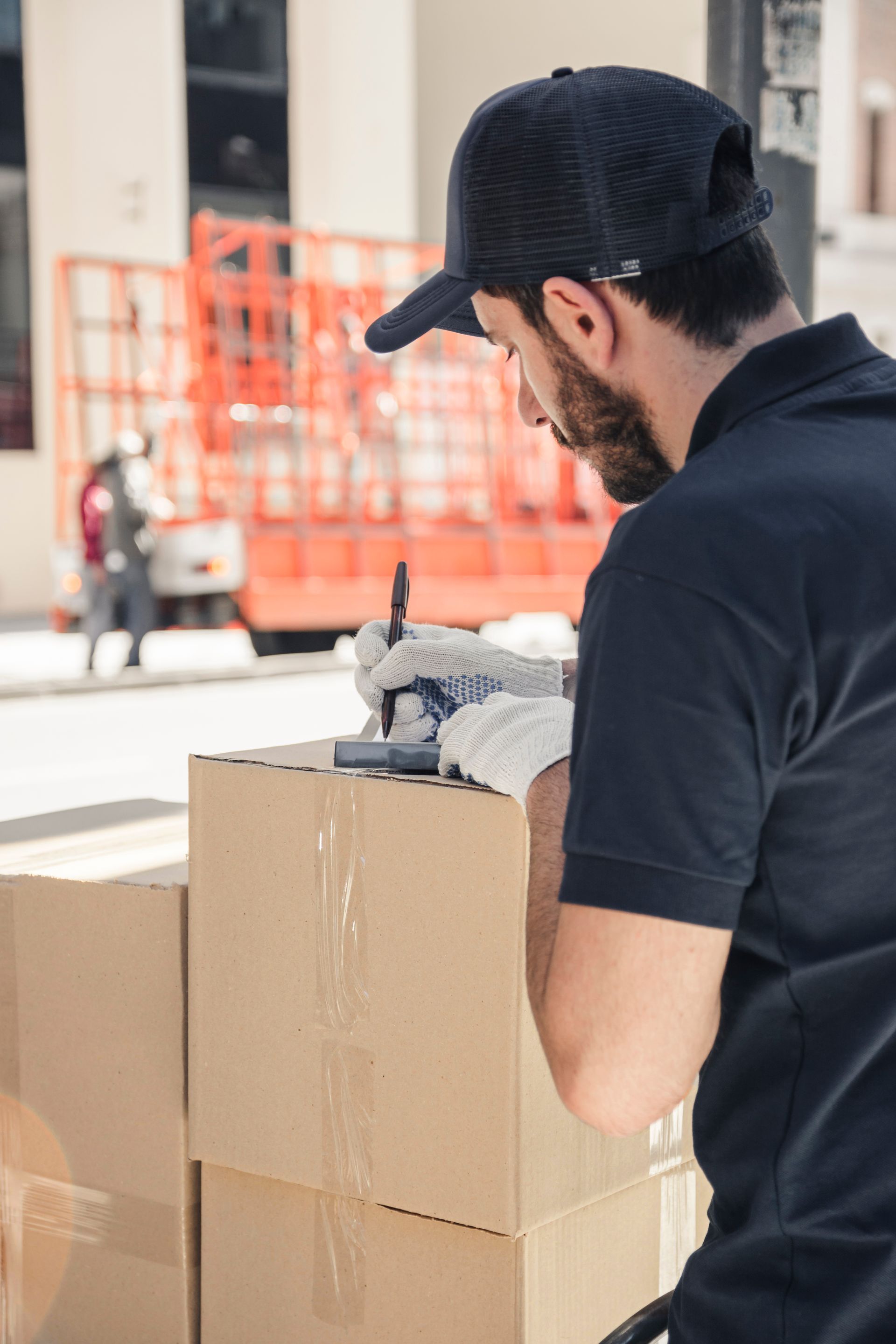 A delivery man is writing on a cardboard box.