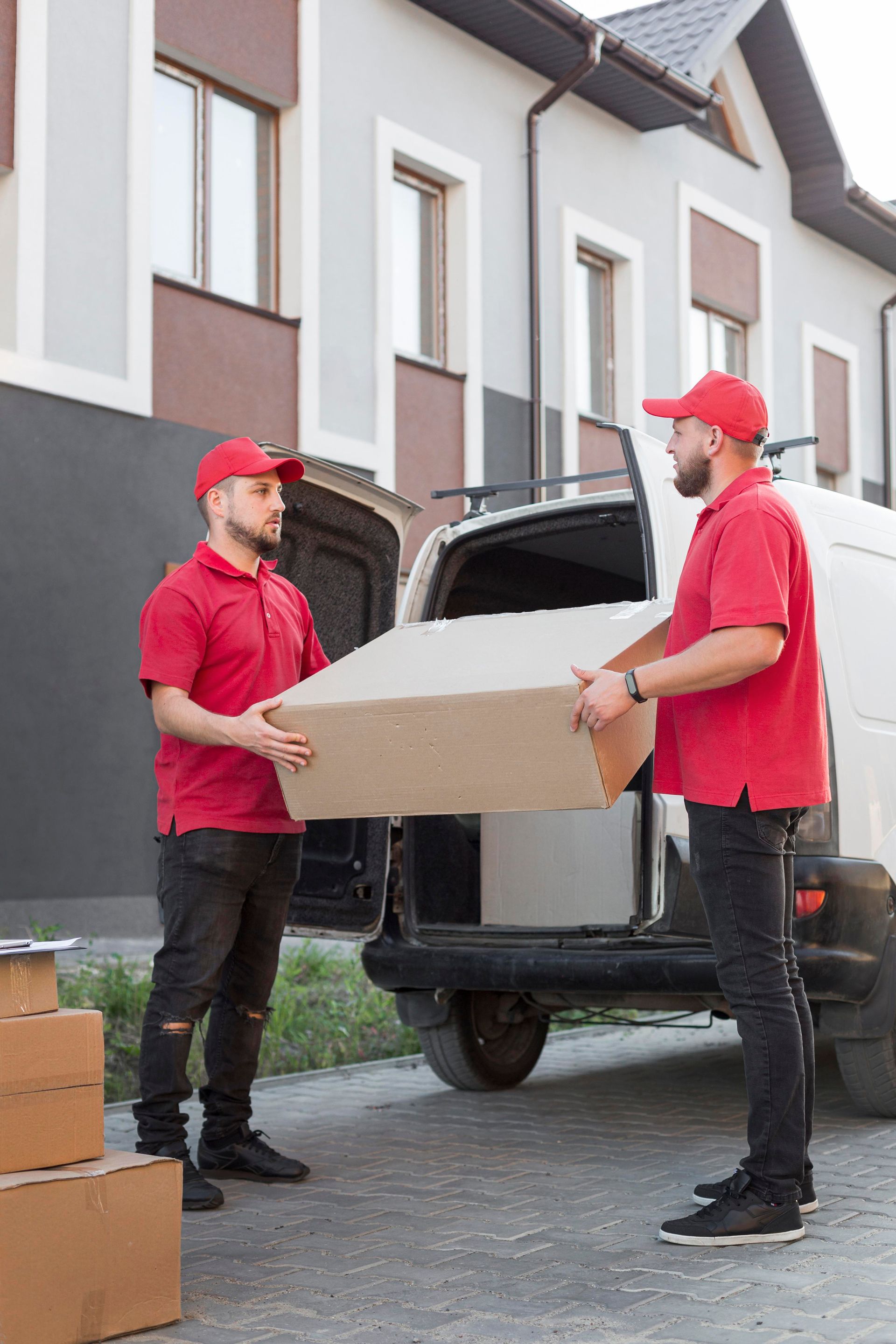 Two delivery men are carrying boxes out of a van.