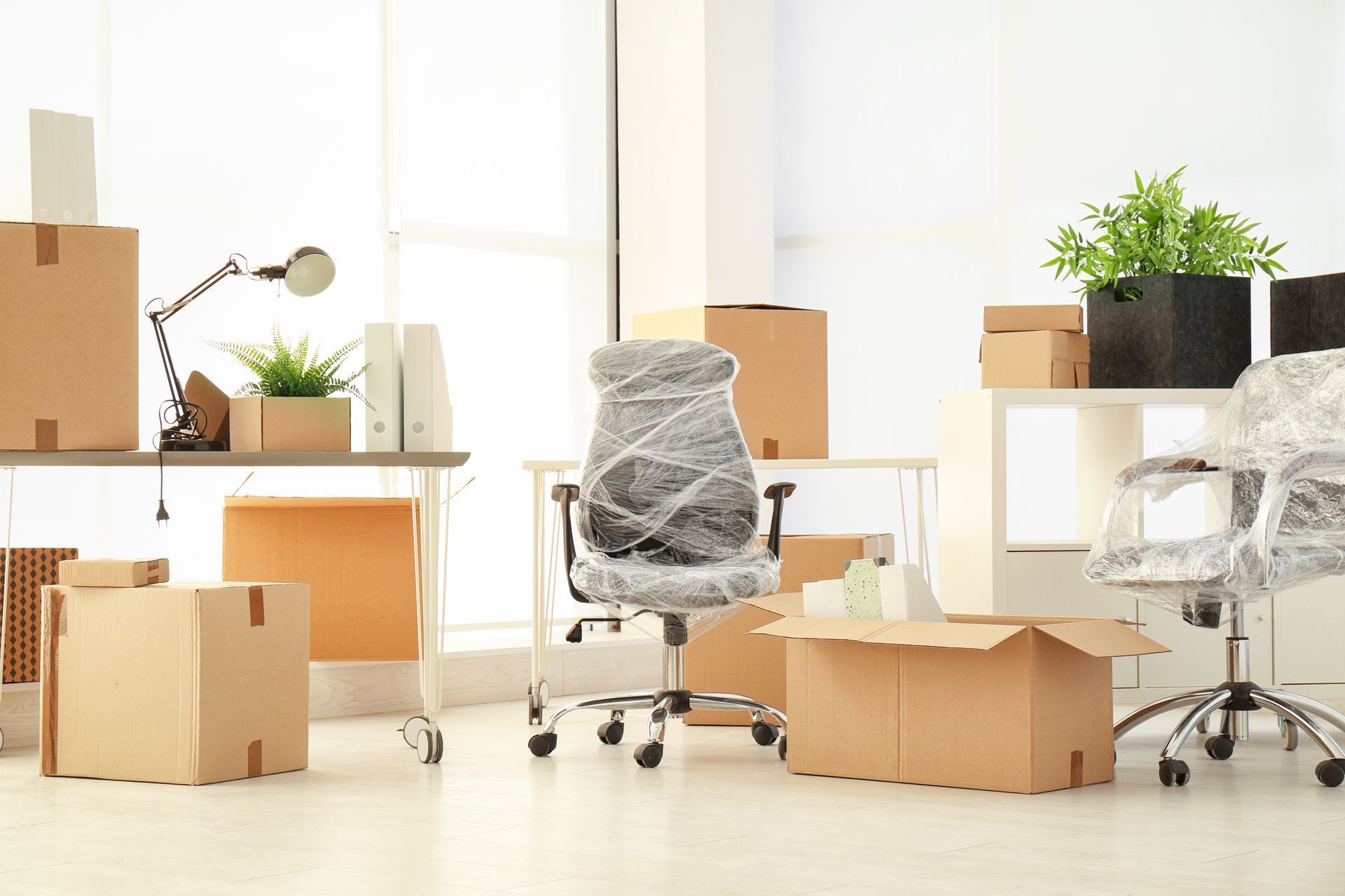 An office filled with boxes and a chair wrapped in plastic.