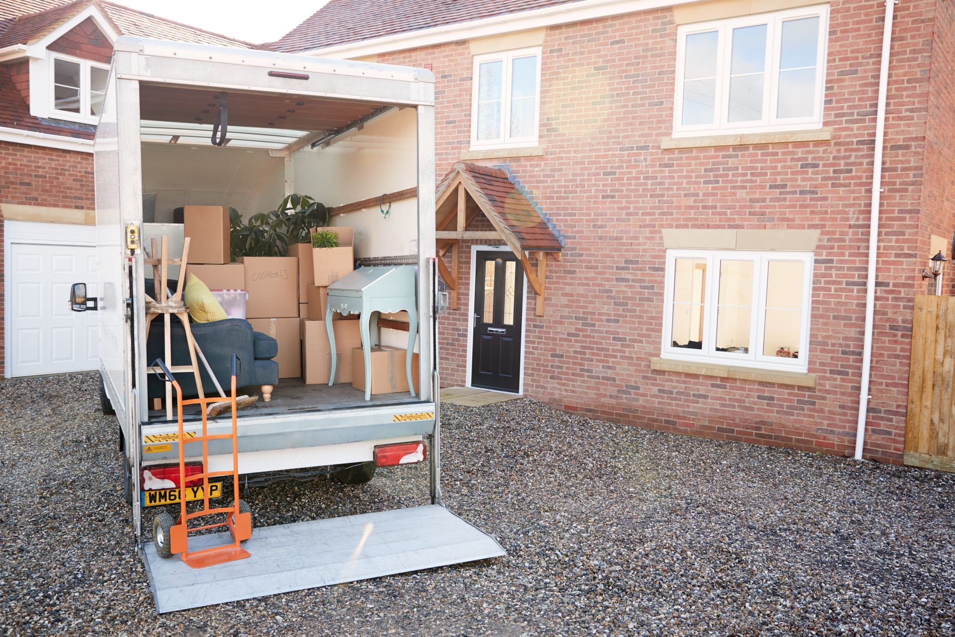 A moving truck is parked in front of a brick house.