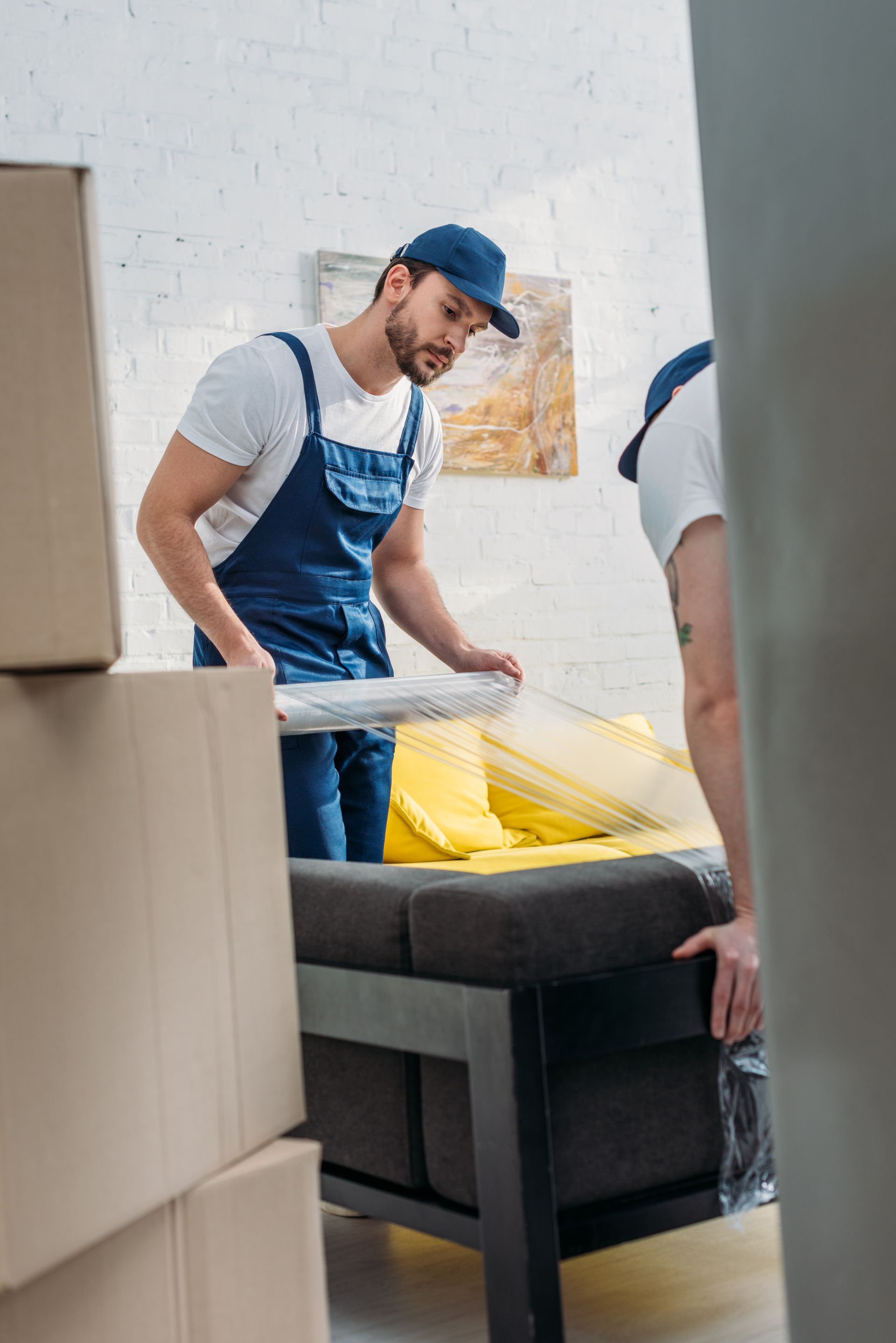 Two men are moving a couch in a living room.